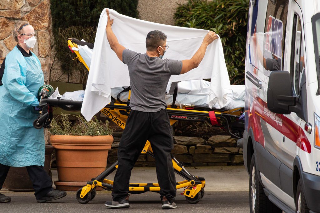  Healthcare workers transport a patient on a stretcher into an ambulance on February 29, 2020 in Kirkland, Washington. | Photo:Getty Images