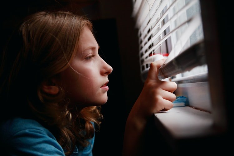 Une petite fille qui regarde par la fenêtre. | Photo : Unsplash