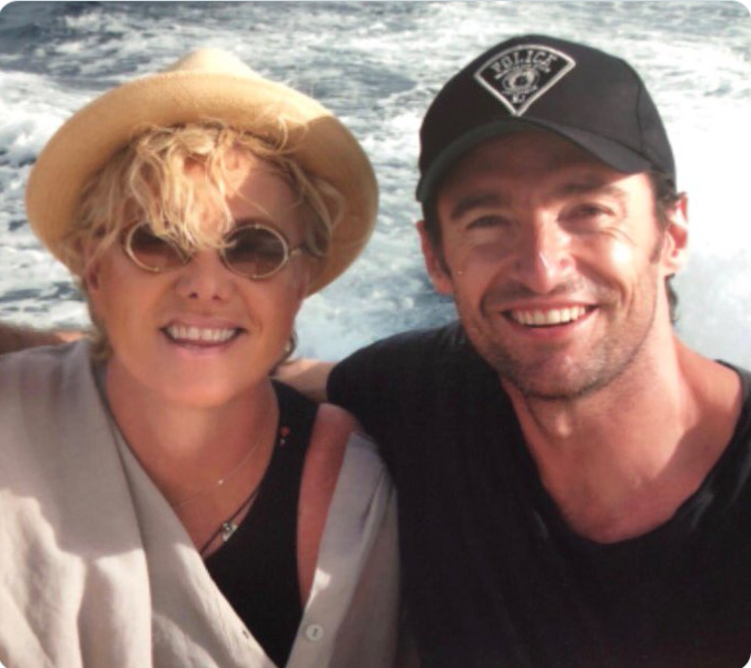 Hugh Jackman and Deborra-Lee Furness smile together during a relaxed boat outing, dressed casually against a backdrop of open water. | Source: X/Hugh Jackman