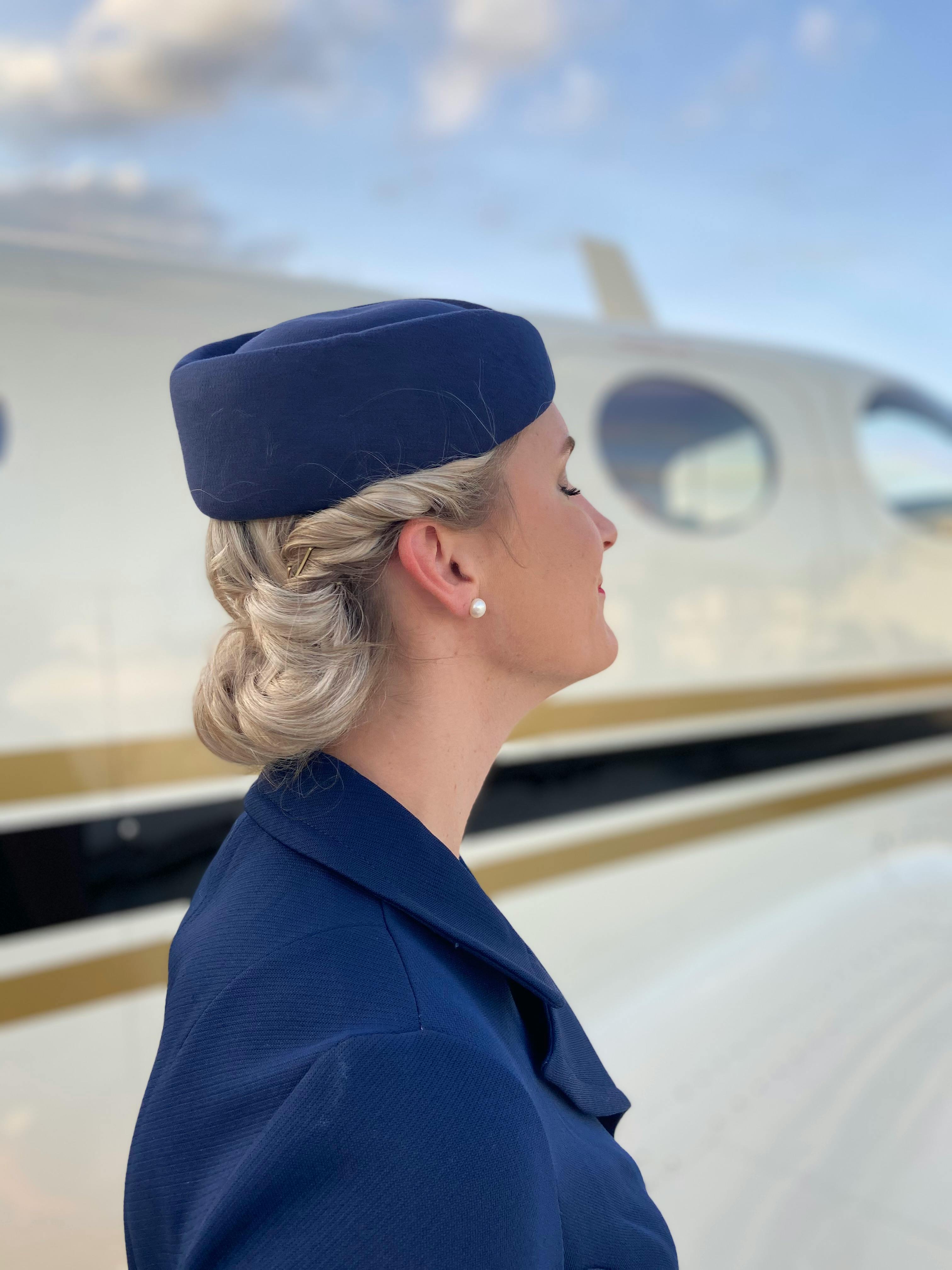 A happy flight attendant standing next to a plane | Source: Pexels