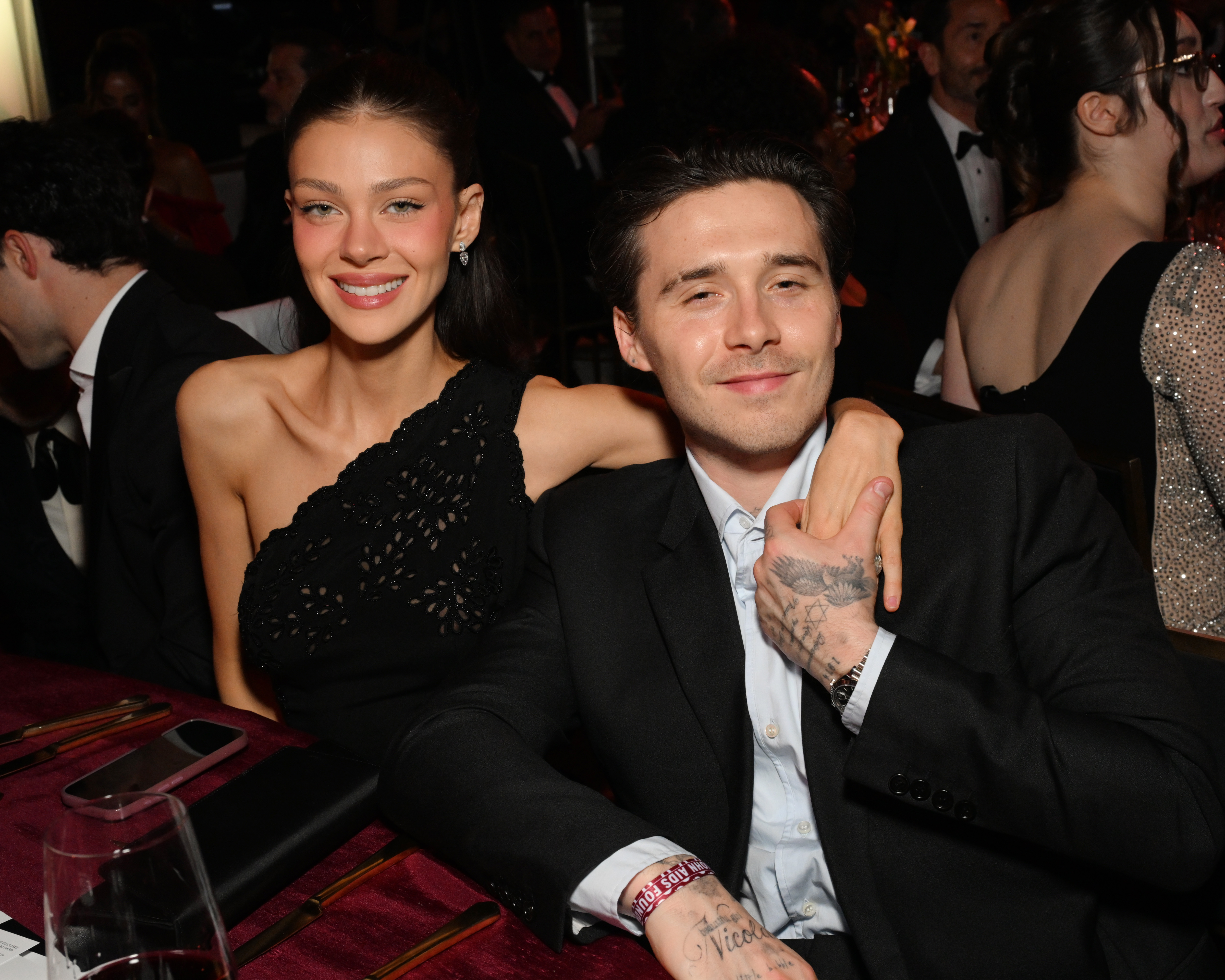 Brooklyn Peltz Beckham, 27, and his wife, Nicola Peltz Beckham, were photographed together at the Elton John AIDS Foundation's 34th Annual Academy Awards Viewing Party on 15 March 2026 in California, United States — an event hosted by Brooklyn's godfather, Sir Elton John, amid the couple's ongoing rift with the Beckham family. Nicola wore a black one-shoulder crochet dress, her dark hair worn down, while Brooklyn donned a black suit over an open-collar shirt.