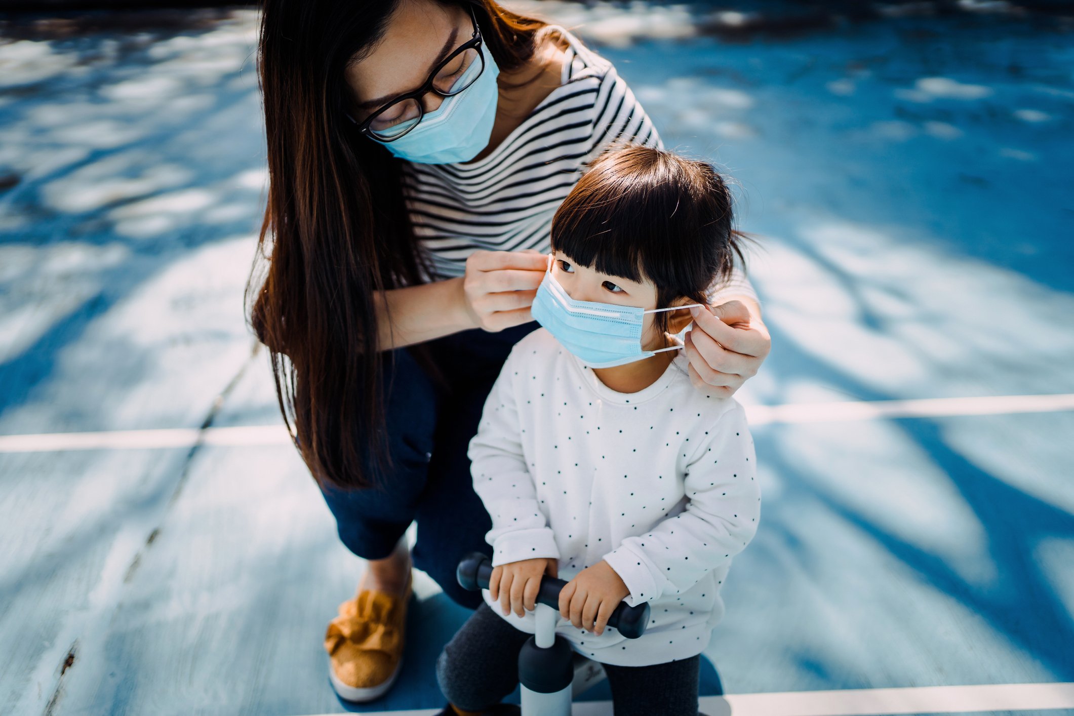Joven madre poniéndole una mascarilla quirúrgica a su hija.| Foto: Getty Images Joven madre poniéndole una mascarilla quirúrgica a su hija.| Foto: Getty Images