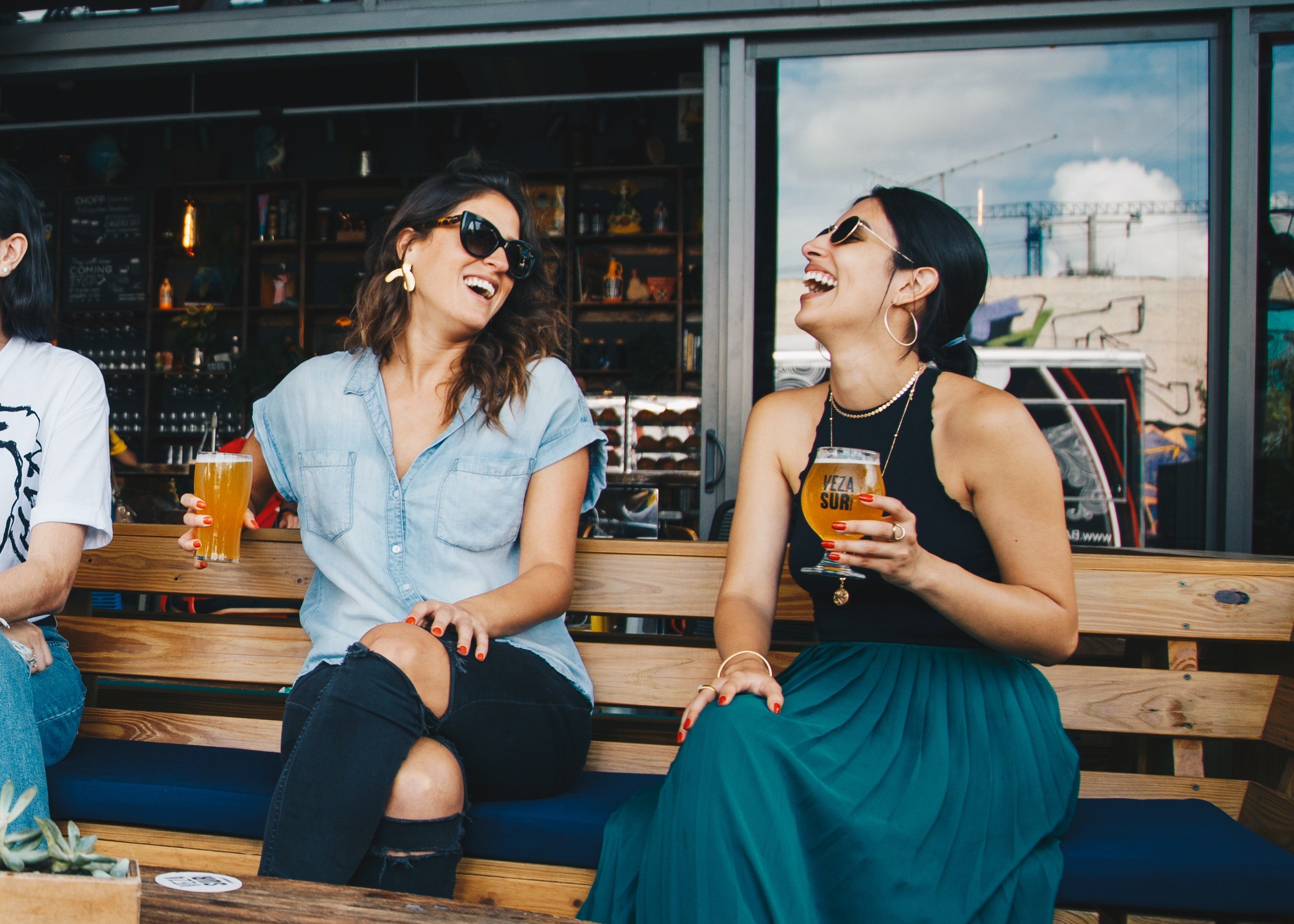 Dos amigas riendo mientras beben un cóctel en un bar. | Foto: Pexels