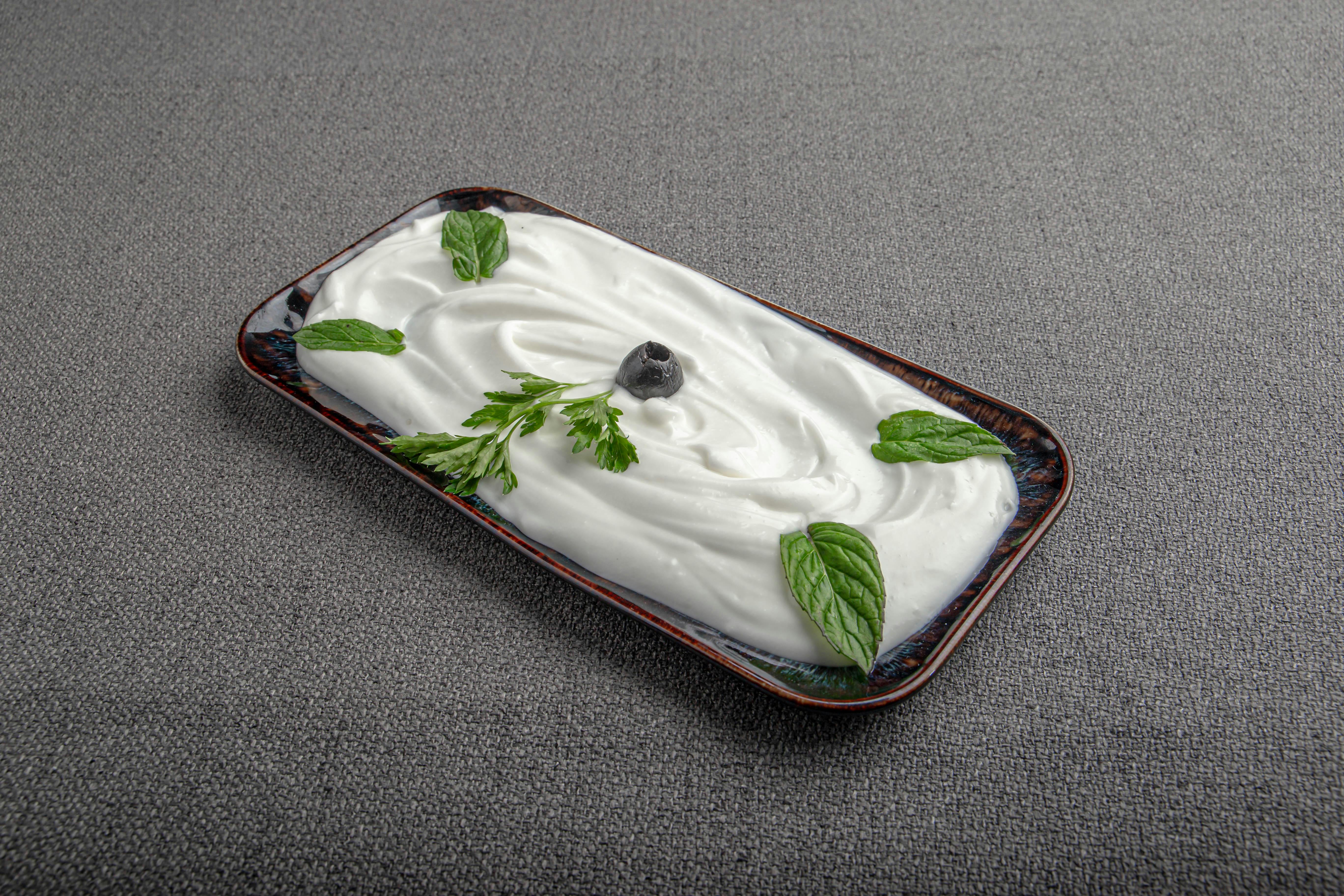 A smooth, creamy serving of Greek yoghurt is presented with fresh mint and a single berry, highlighting its thick texture and simple appeal. | Source: Pexels