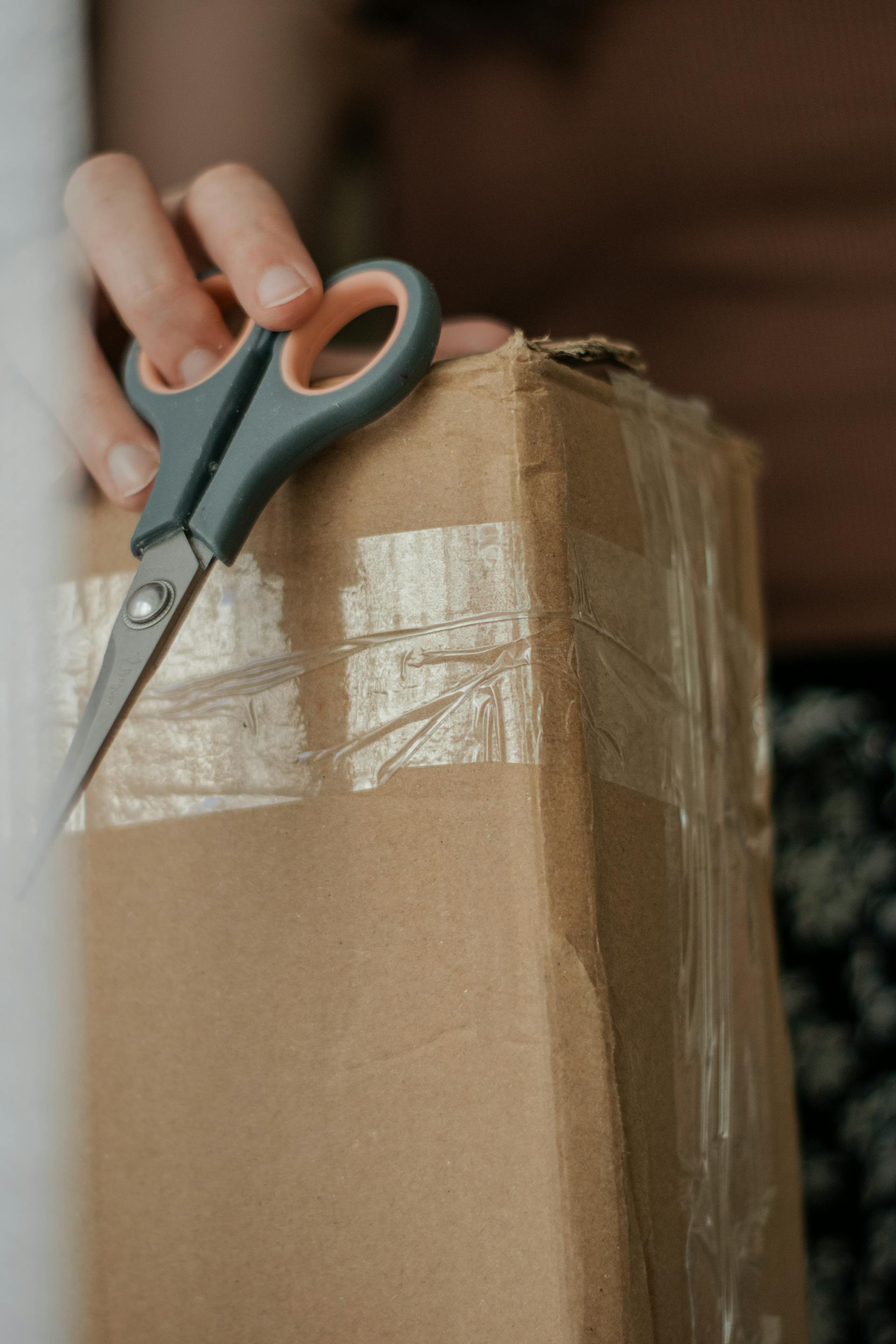 Close-up shot of a woman holding a cardboard box and scissors | Source: Pexels