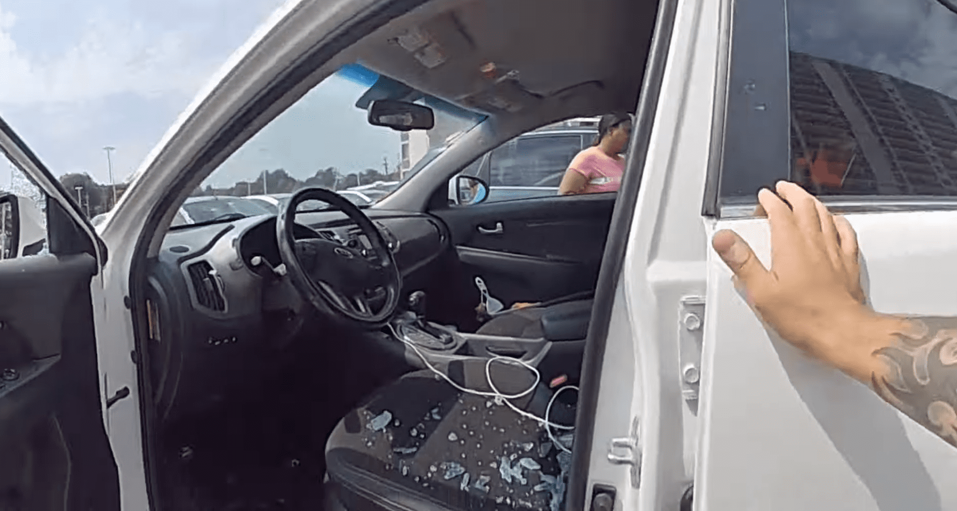 A police officer opening the front door of a car after smashing the window open, with glass pieces on the seat | Source: youtube.com/Euclid Police Department
