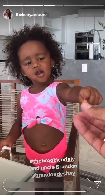 Kenya Moore's daughter, Brooklyn, dressed in pink underwear and a pink and white crop top seen playing with her uncle | Photo: Instagram/thekenyamoore