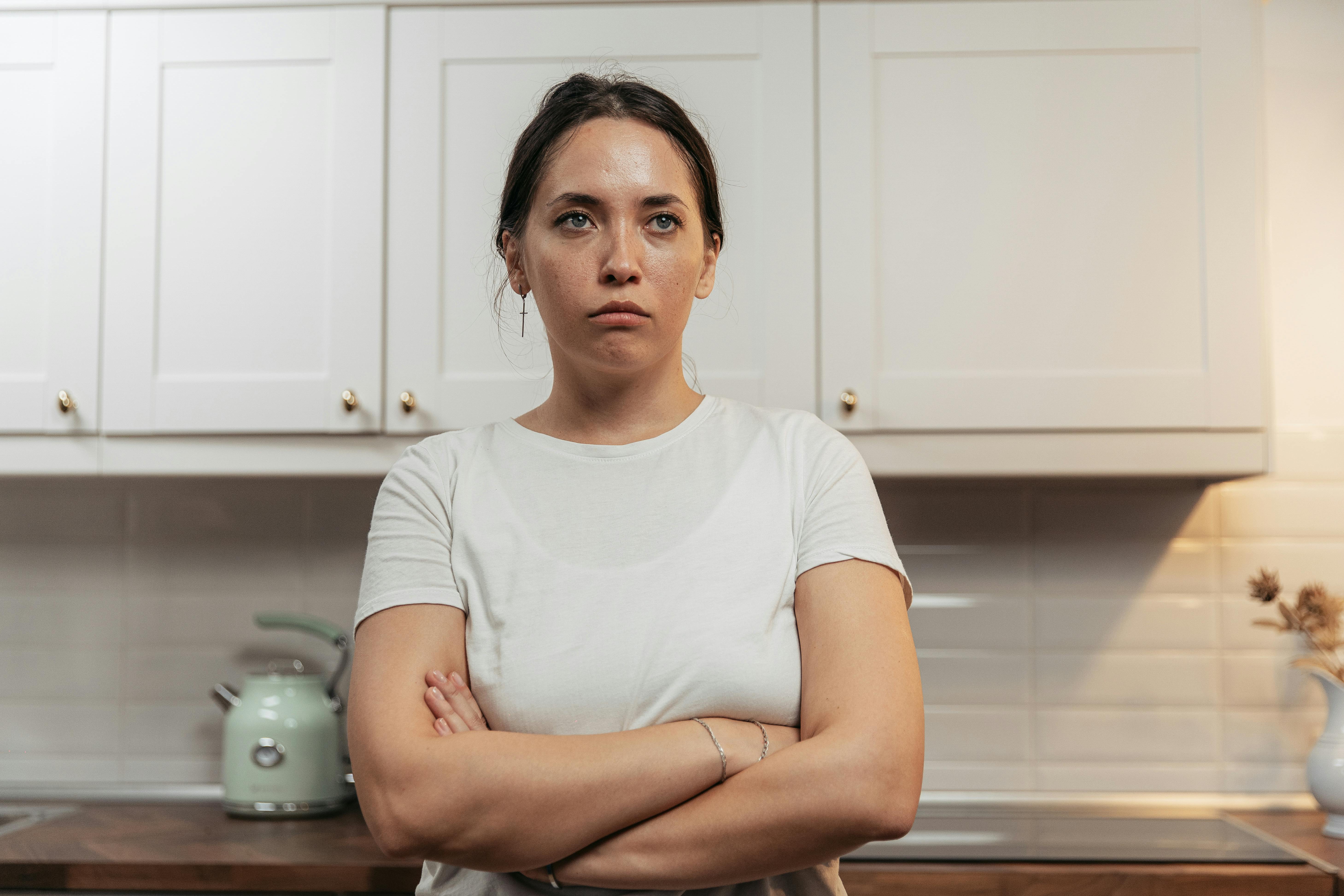 A woman standing in the kitchen feeling upset | Source: Pexels
