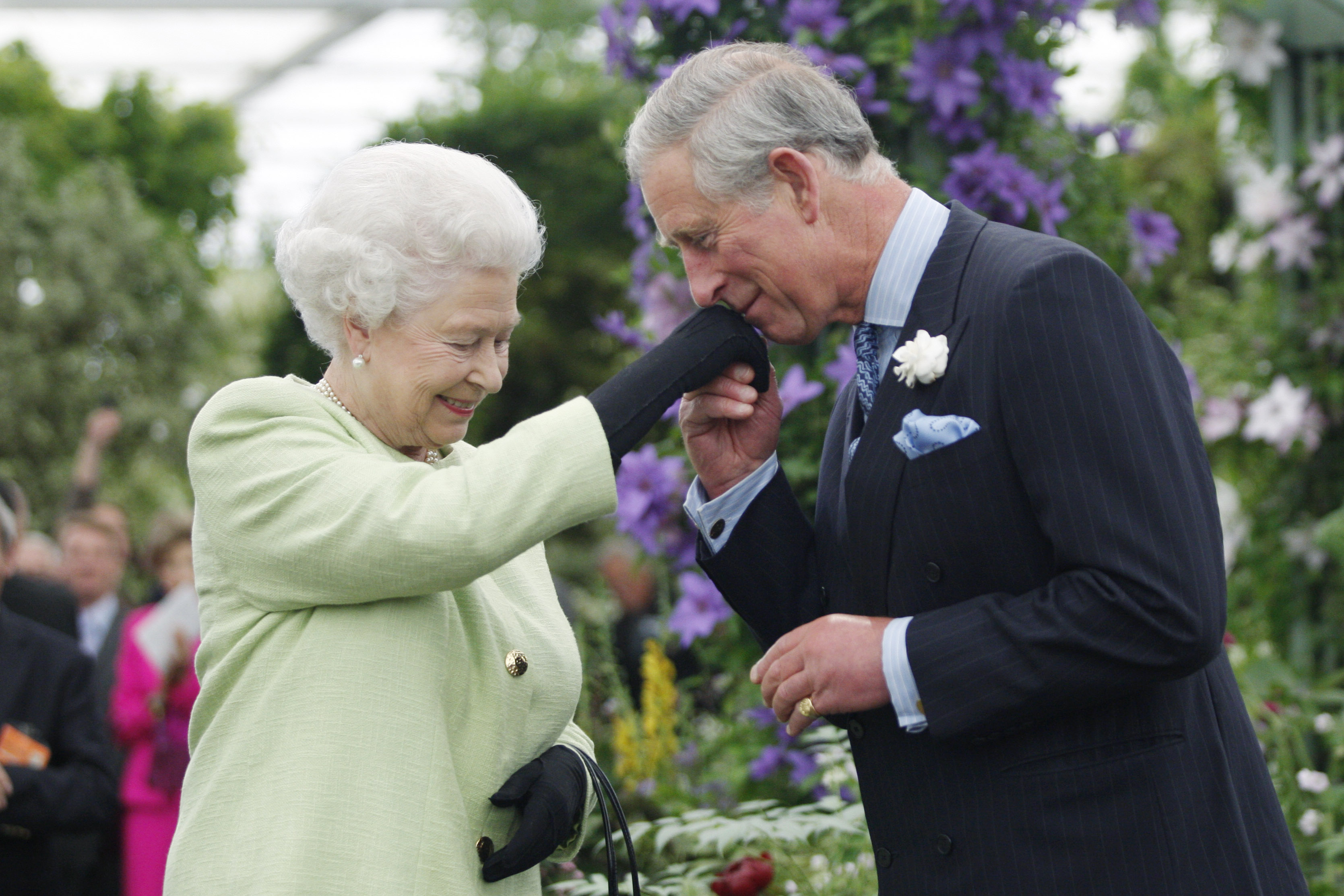 During a visit to the Chelsea Flower Show in London on 18 May 2009, Queen Elizabeth II is seen presenting Prince Charles, Prince of Wales, with the Royal Horticultural Society's prestigious Victoria Medal of Honour, as he bows to kiss her gloved hand, marking a moment of recognition for his long-standing commitment to environmental and horticultural causes.