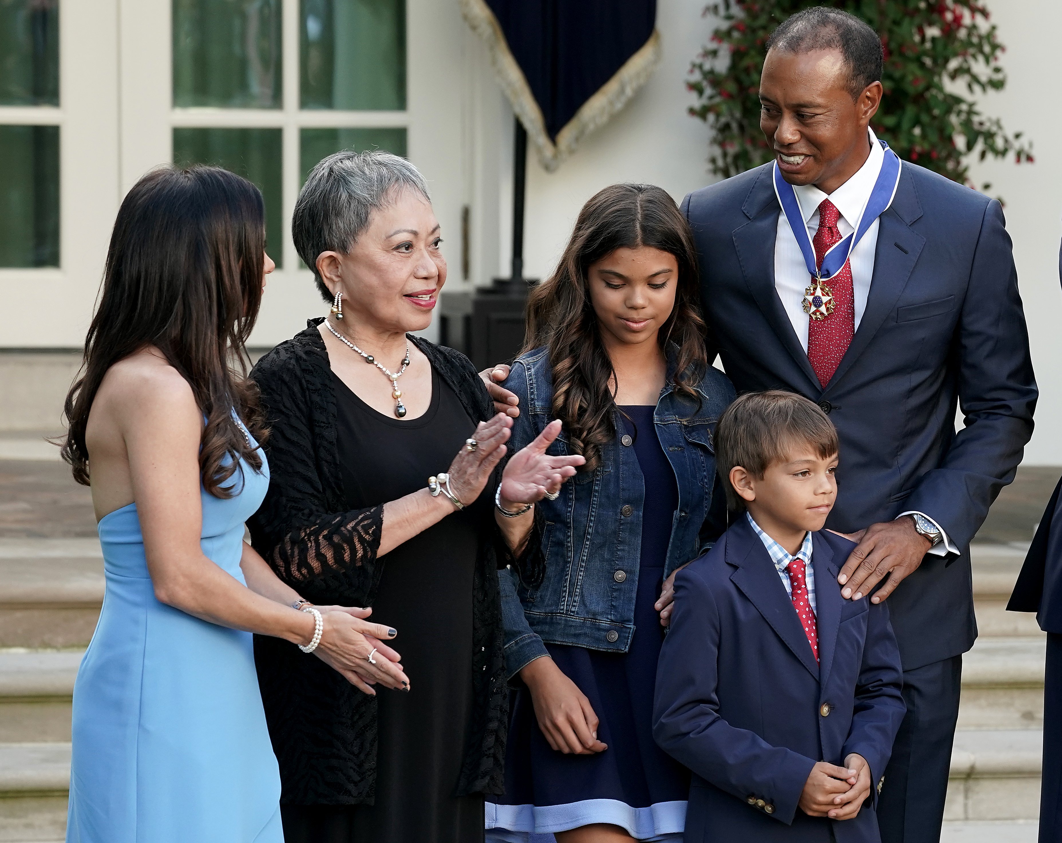 Professional golfer Tiger Woods (R) is joined by his mother Kultida Woods (2nd L), children Sam Alexis Woods and Charlie Axel Woods and girlfriend Erica Herman during his Medal of Freedom ceremony in the Rose Garden at the White House May 06, 2019 in Washington, DC. | Source: Getty Images