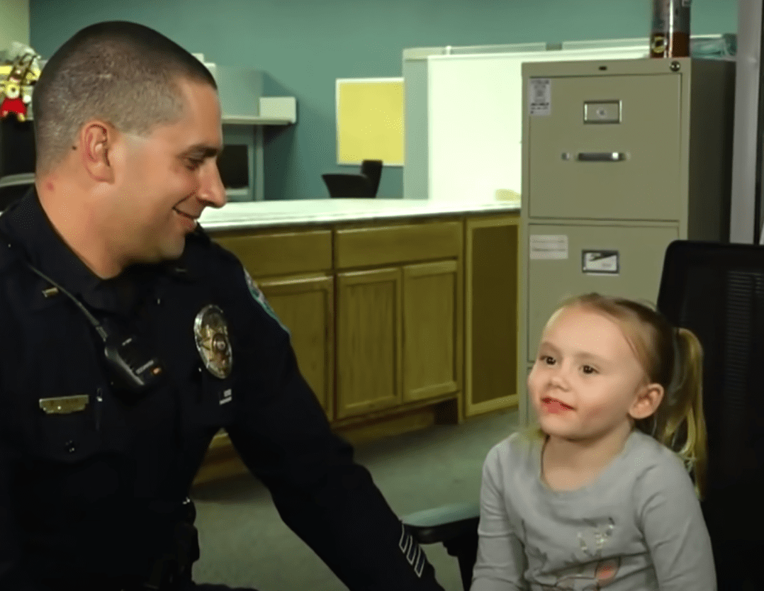 Neben ihr sitzt ein Polizist, der sich um den Fall häuslicher Gewalt eines kleinen Mädchens gekümmert hat und ist jetzt ihr Adoptivvater | Quelle: Youtube/Inside Edition