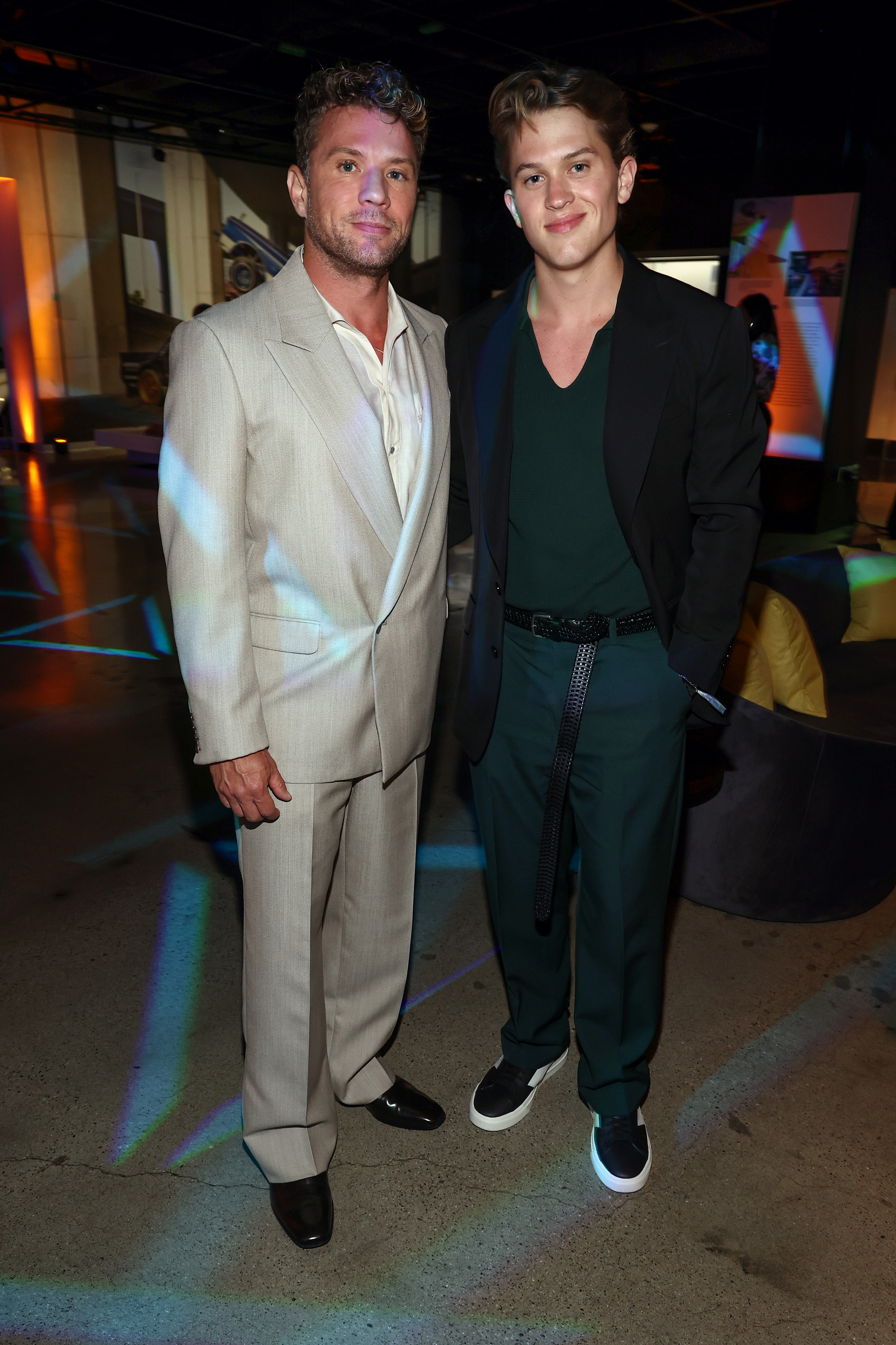 Ryan Phillippe and Deacon Phillippe strike a poised pose inside the Petersen Automotive Museum during the "Motorheads" screening. Ryan sports a neutral suit while Deacon pairs a deep green knit with a black blazer, their coordinated looks highlighting their father-son bond.