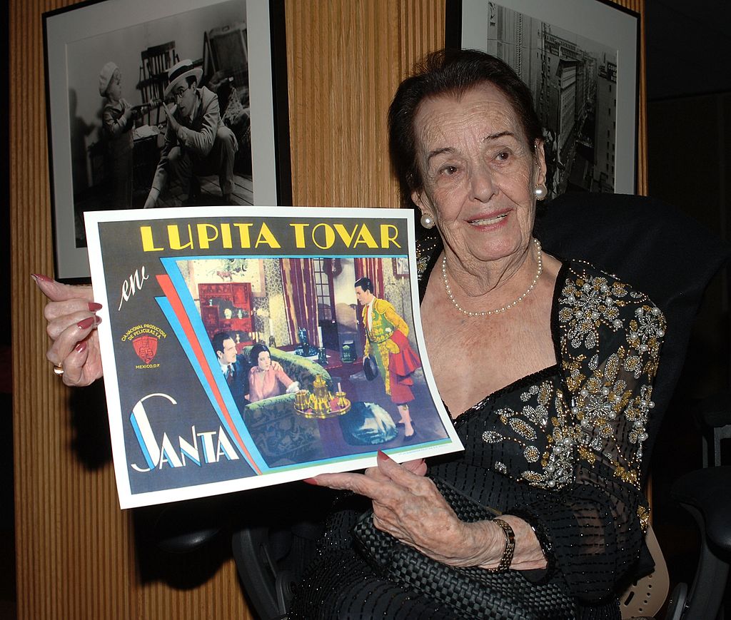 Lupita Tovar sostiene un póster de una de sus películas en su tributo en la Academia de Artes y Ciencias Cinematográficas el 7 de diciembre de 2006 en Beverly Hills, California. | Imagen: Getty Images Lupita Tovar sostiene un póster de una de sus películas en su tributo en la Academia de Artes y Ciencias Cinematográficas el 7 de diciembre de 2006 en Beverly Hills, California. | Imagen: Getty Images