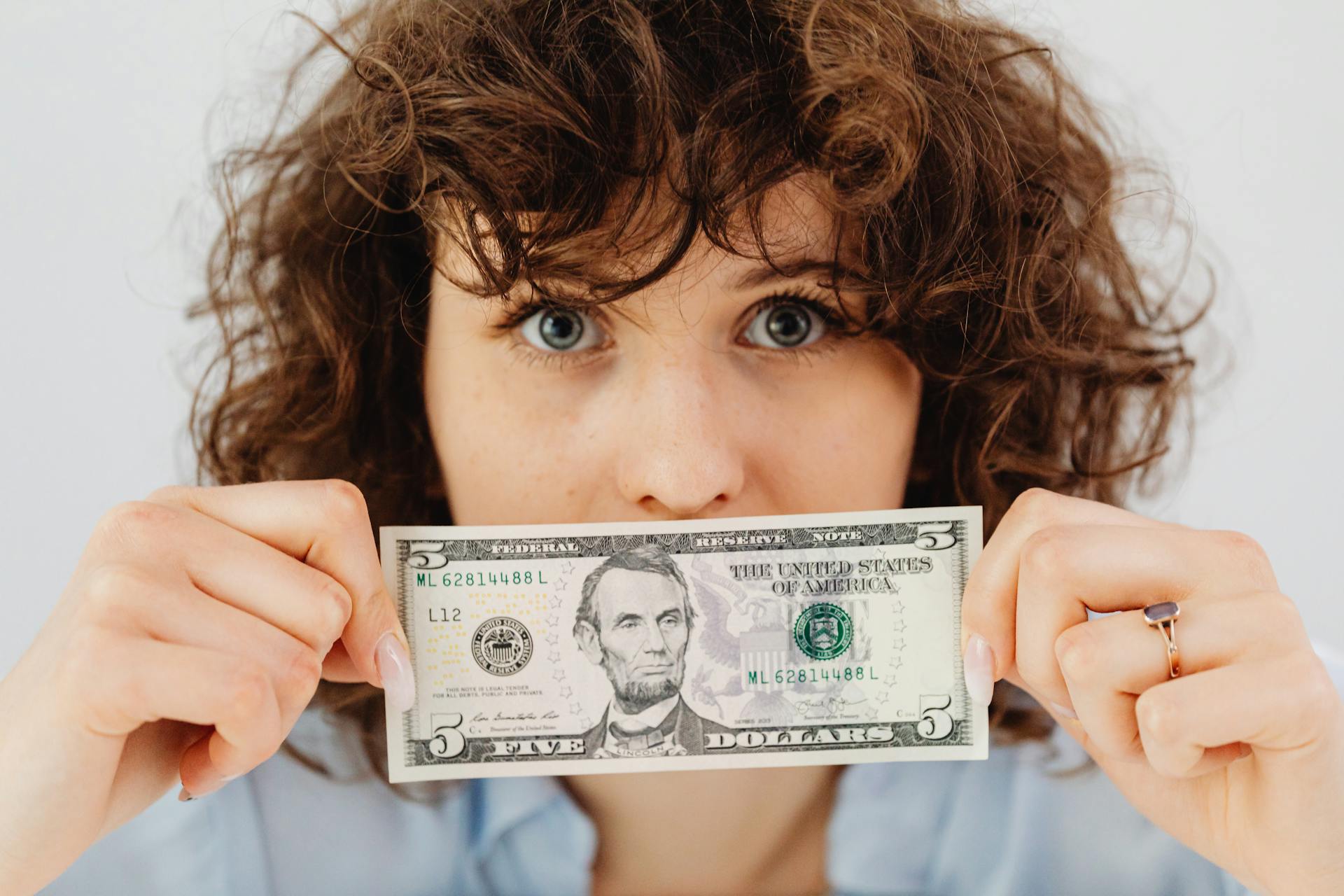 A woman holding a five-dollar bill | Source: Pexels