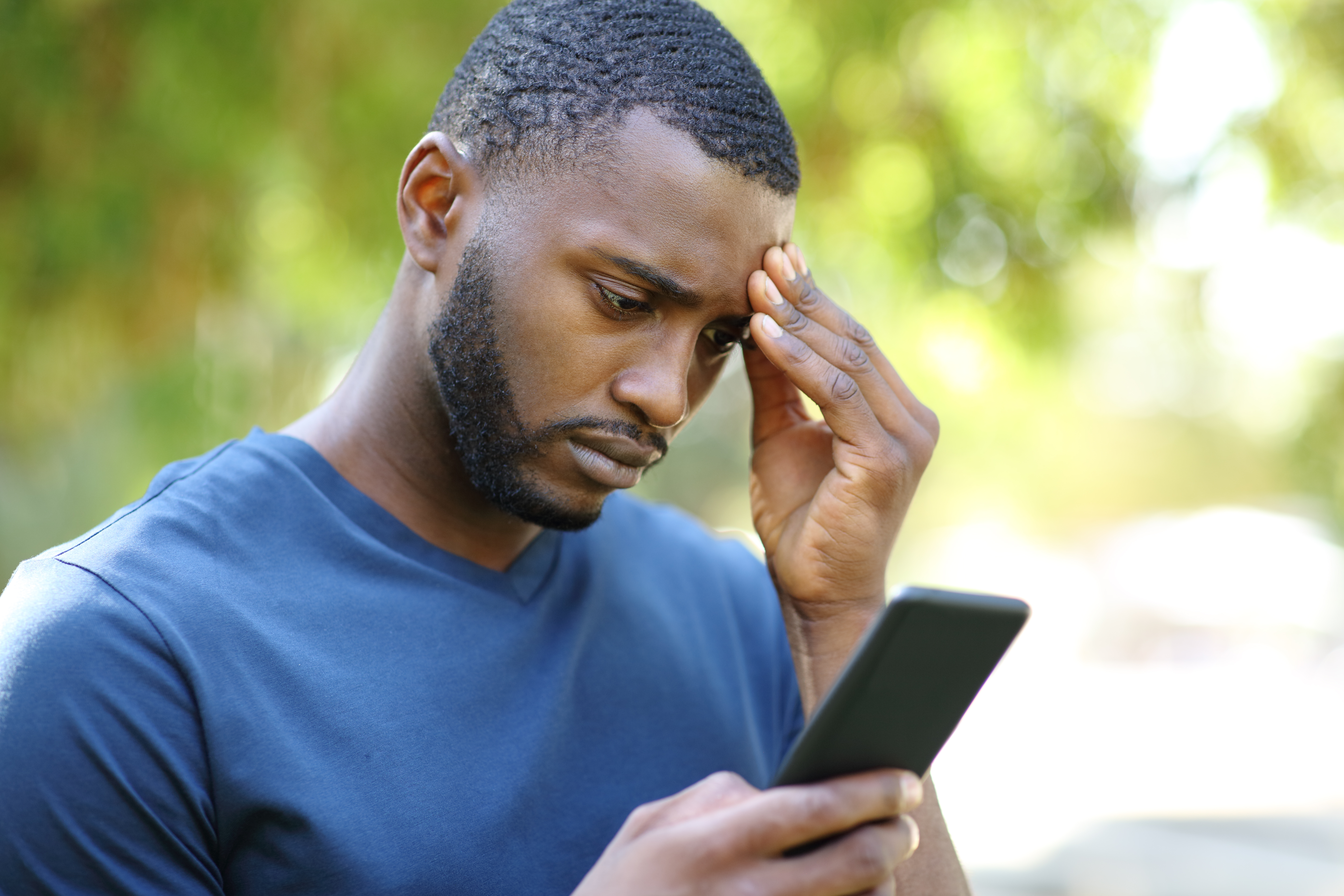 Worried black man checking smart phone in a park | Source: Getty Images