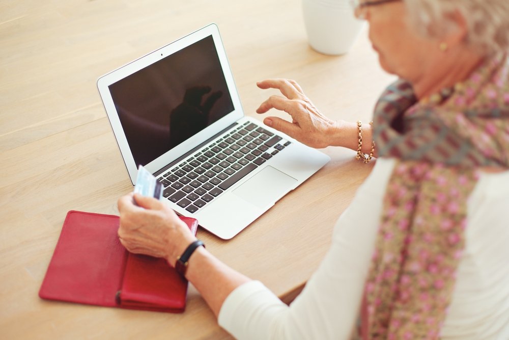 Anciana sentada frente a un escritorio con una computadora portátil. | Foto: Shutterstock