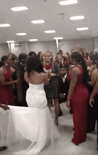 Bride Sierra McGuinty walks to her brother's girlfriend to hand her her bouquet as part of the proposal. | Source: twitter/devon0jones