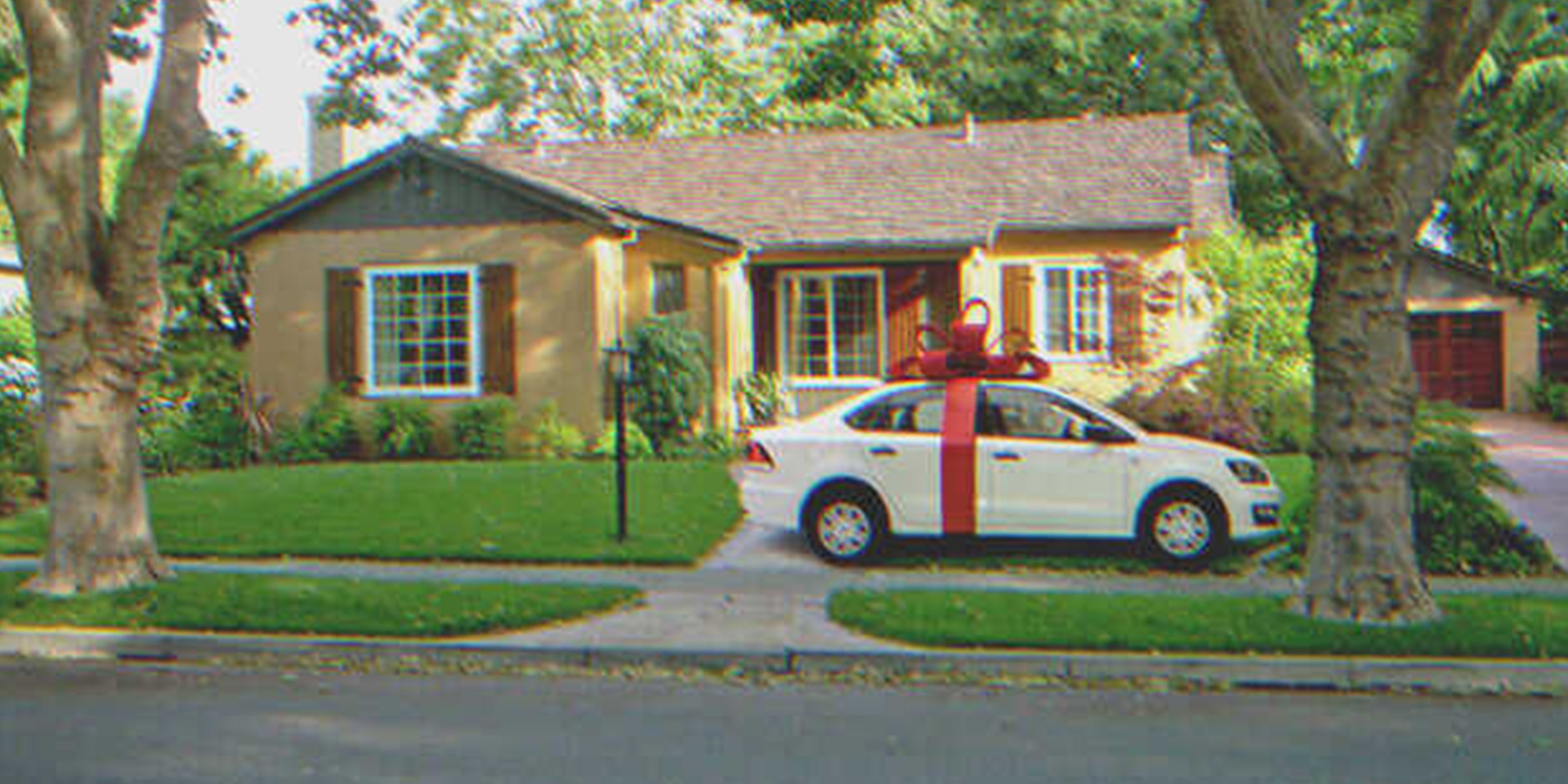 Une voiture avec un ruban devant une maison | Shutterstock    