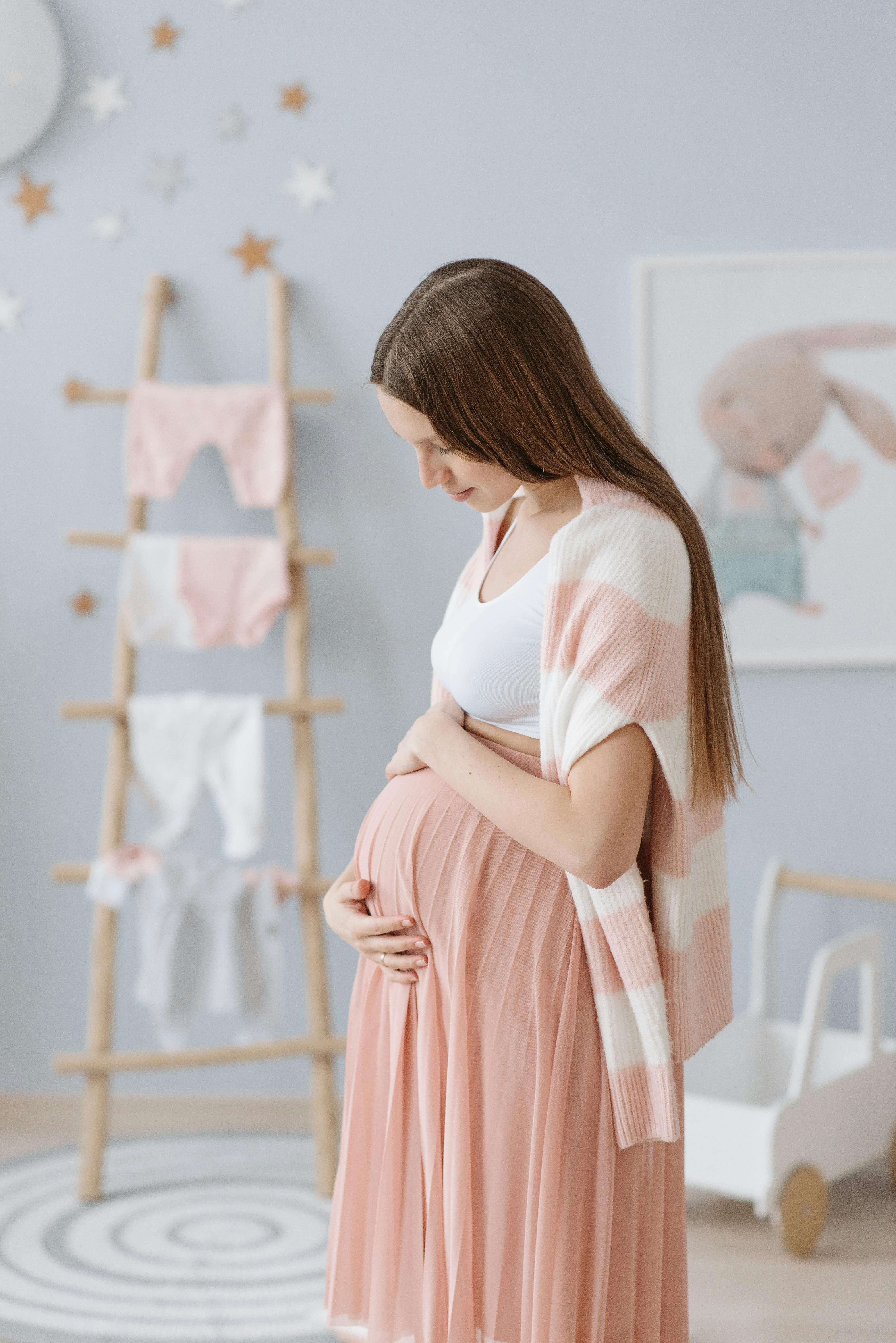 A pregnant woman holding her belly in her upcoming baby's room | Source: Pexels