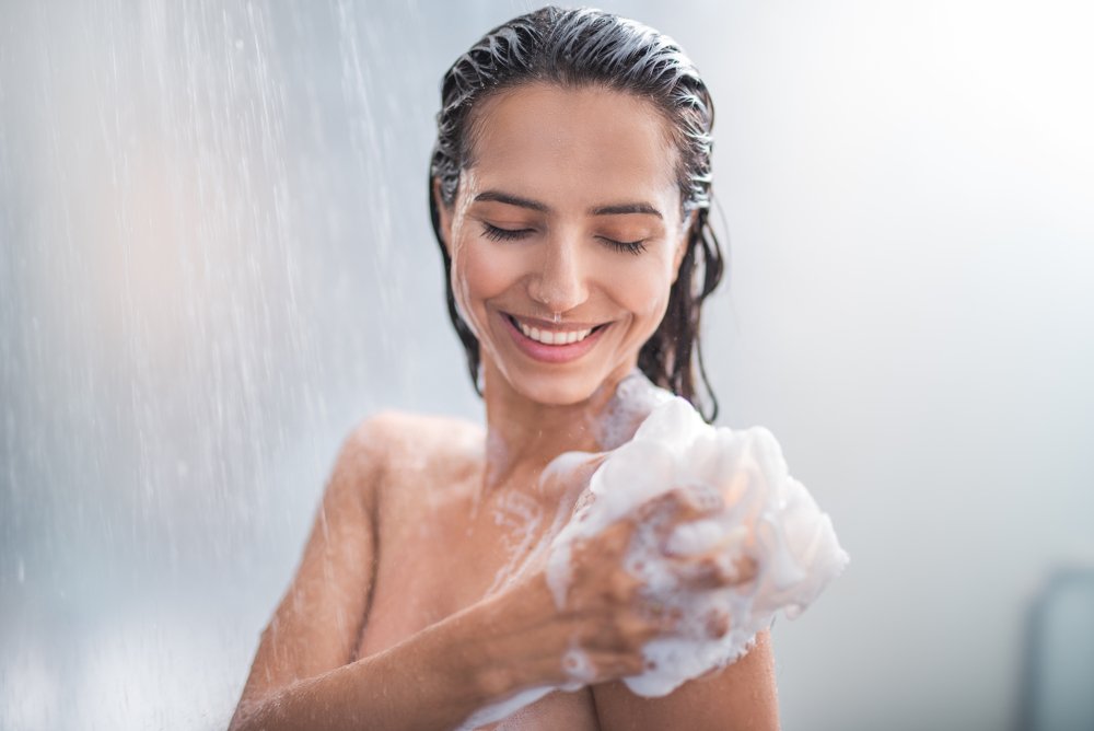 A portrait of happy girl taking a shower. | Photo: Shutterstock