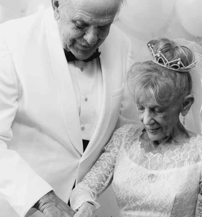 Ein Bild der 79-jährigen Karen Ryan und des 79-jährigen Gary Ryan, die den Moment nachstellen, in dem sie an ihrem Hochzeitstag ihre Torte anschneiden. | Quelle: Instagram.com/nikkiryanphotography