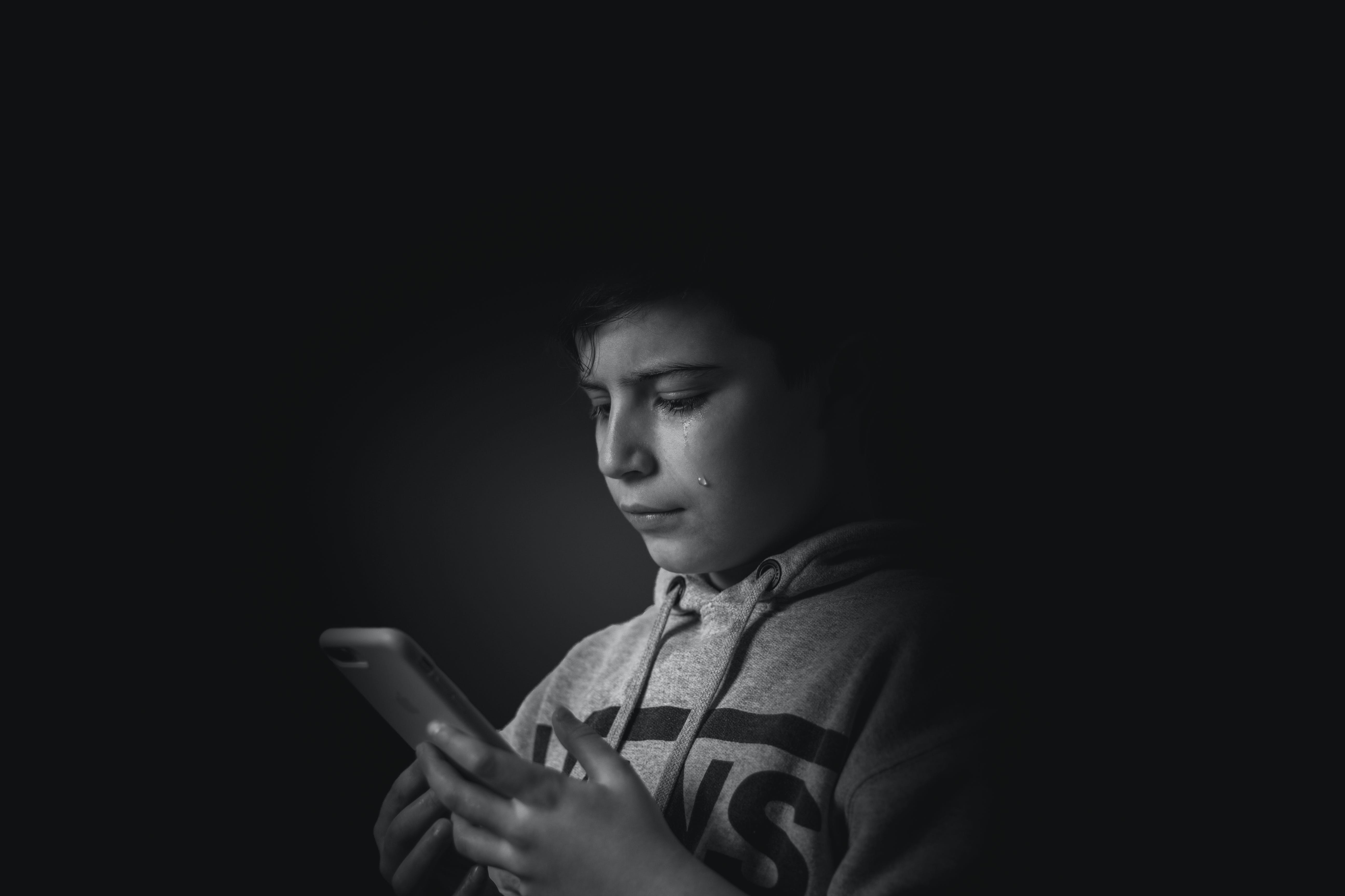Crying boy is looking at the dead phone | Source: Pexels.com