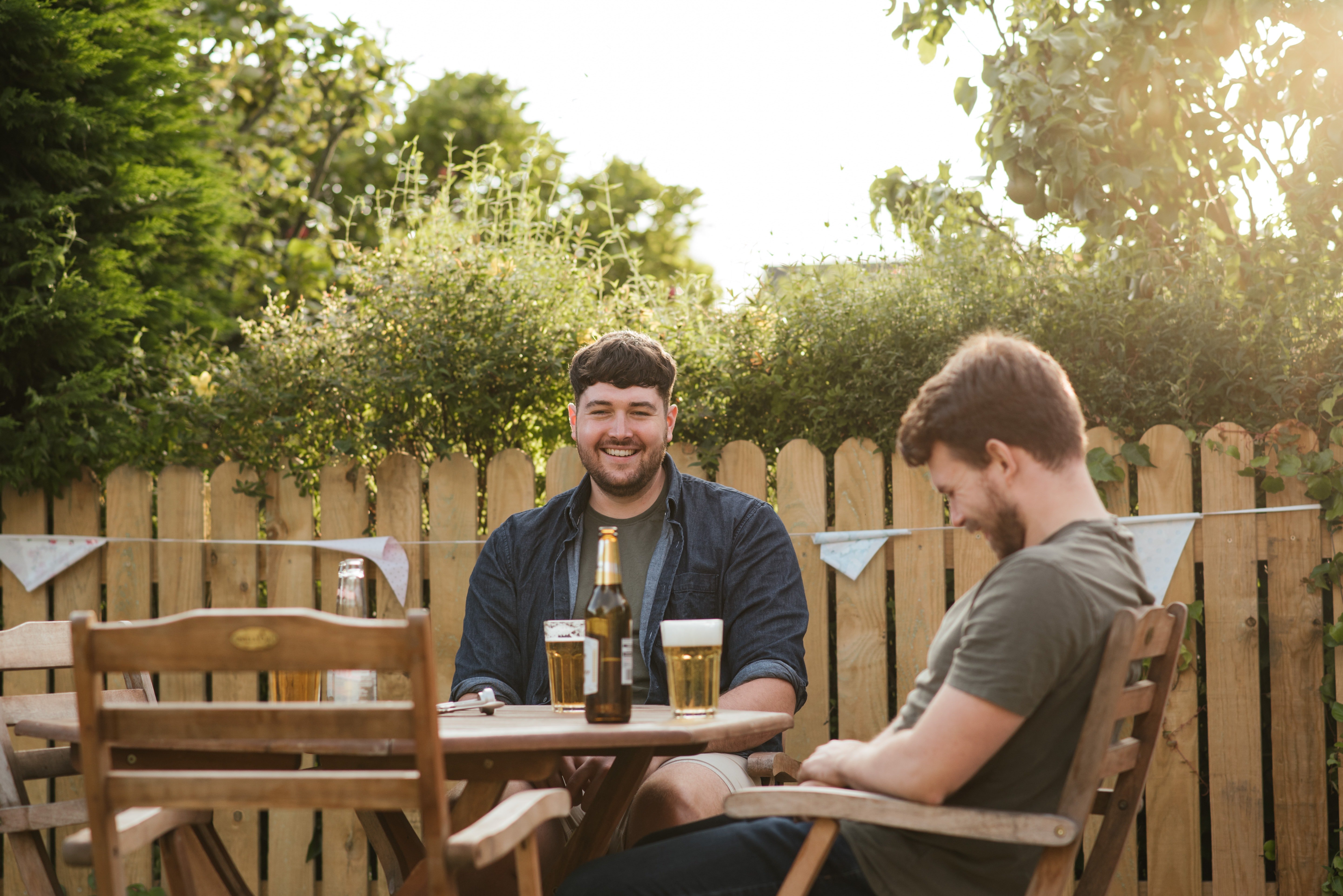 Two men drinking beers outside. | Pexels/  Anete Lusina
