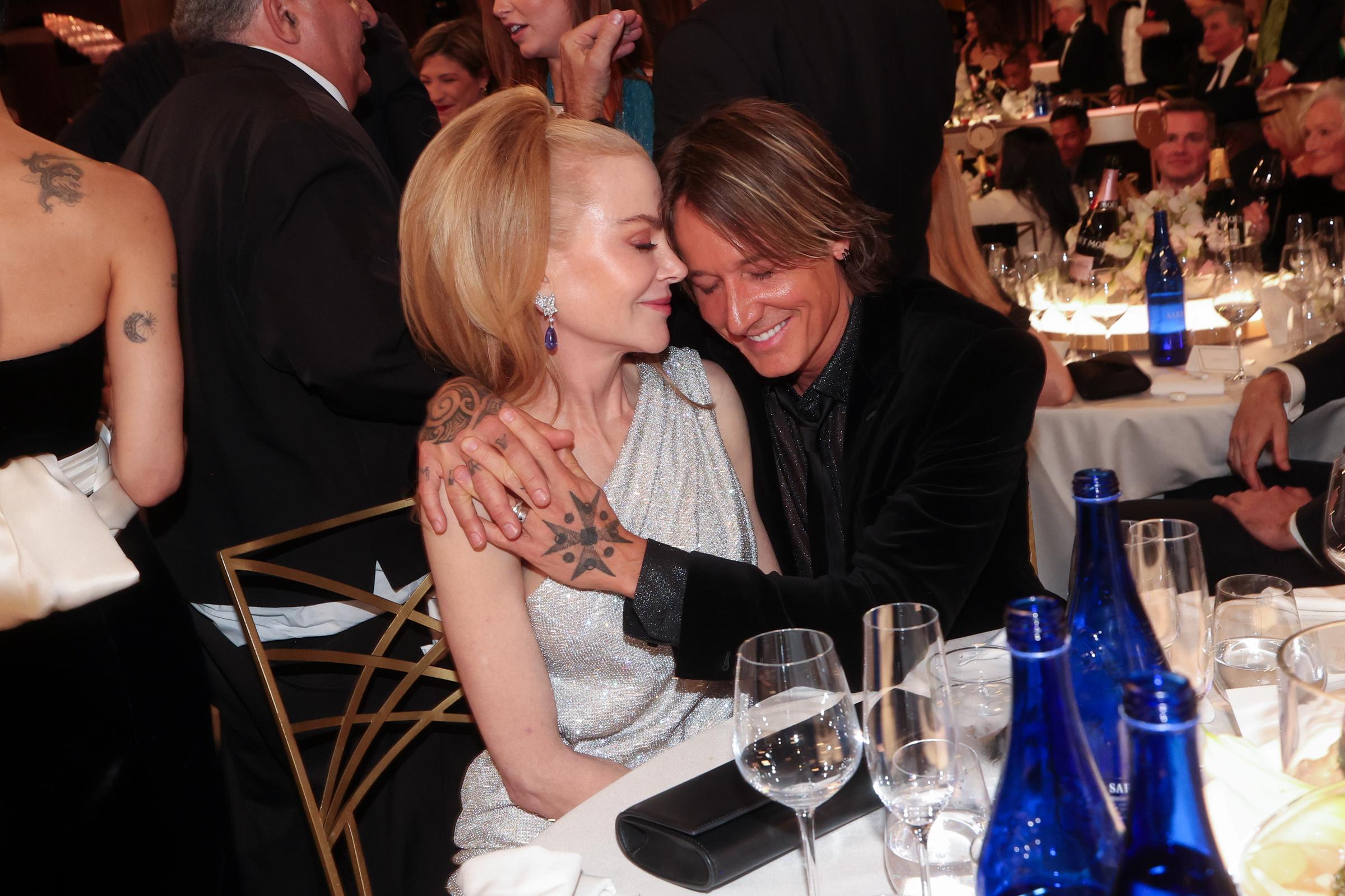 In a soft, almost cinematic moment, Keith Urban presses his forehead to Nicole Kidman's temple, their hands clasped tightly — a whisper of affection in a sea of evening glamour.