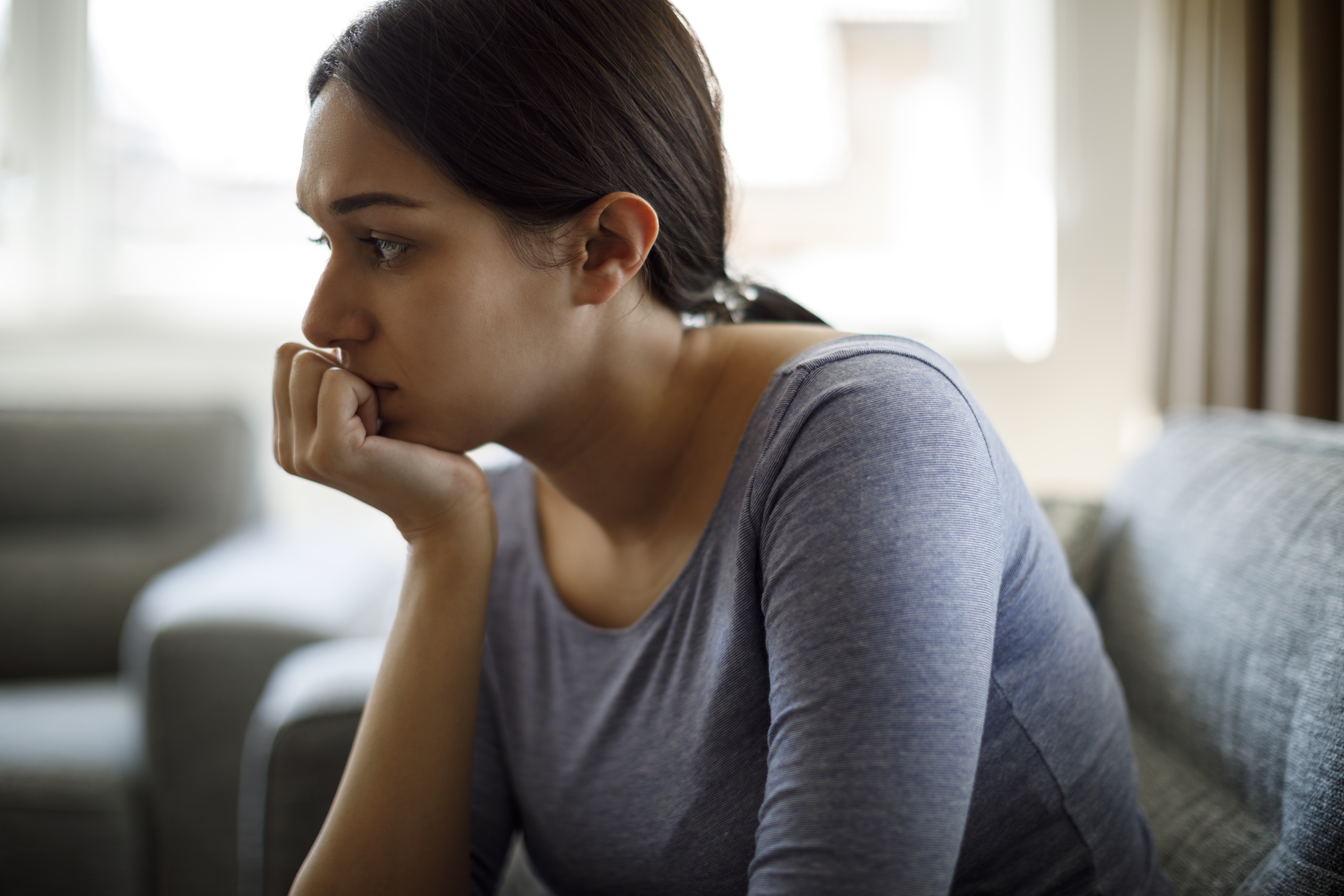 Upset woman sitting on sofa alone at home | Source: Getty Images