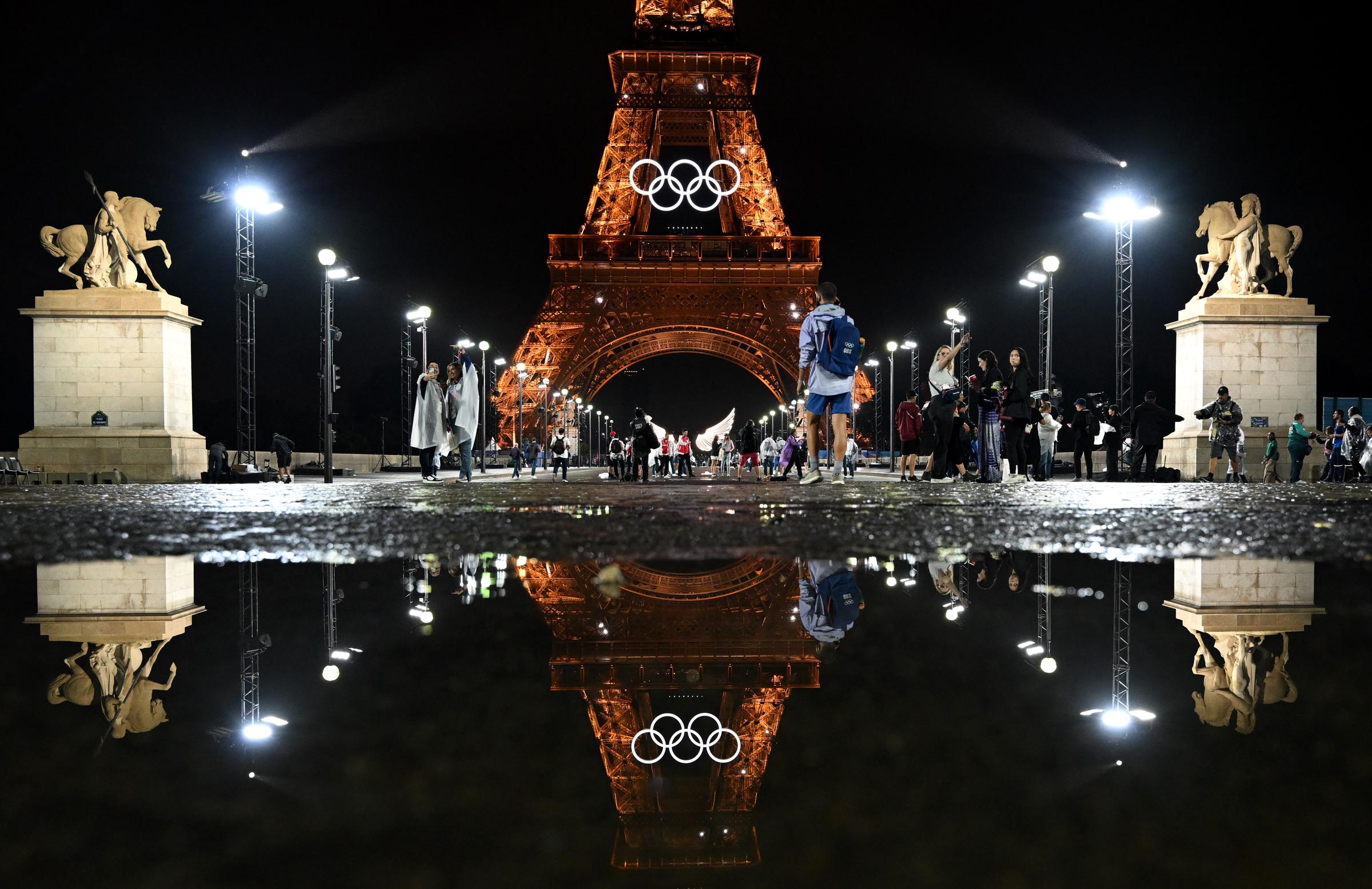 The illuminated Eiffel Tower with the Olympic rings is reflected in a puddle at the opening ceremony of the Summer Olympics, in Paris, France, on July 26, 2024. | Source: Getty Images