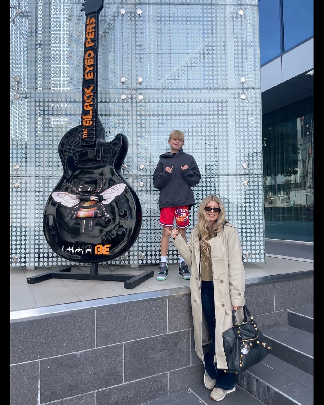 Fergie and her son Axl Duhamel posing next to a guitar dedicated to the Black Eyed Peas and their song "Imma Be" from her birthday tribute posted on August 29, 2025 | Source: Instagram/fergie
