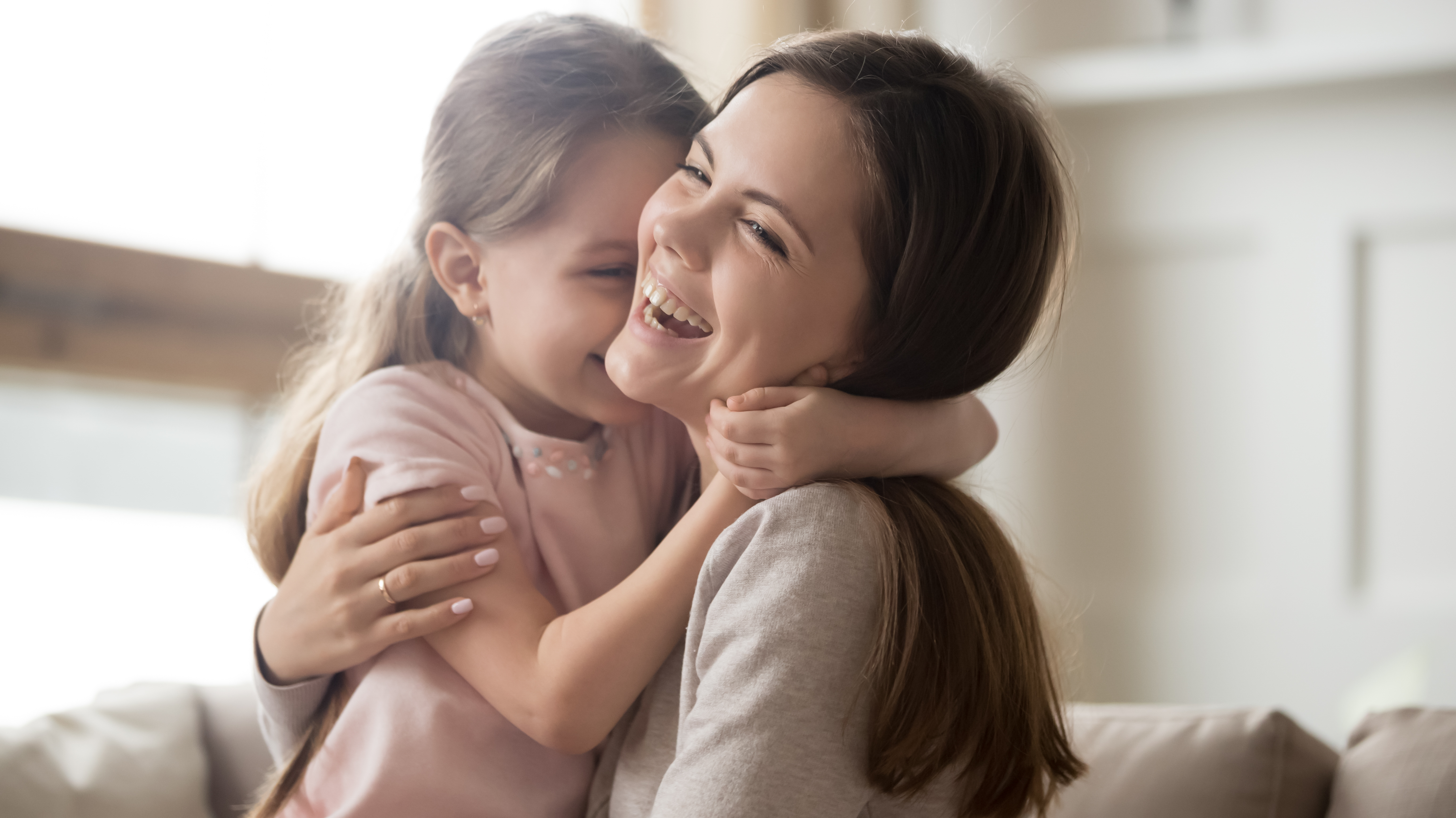 Loving young mother laughing embracing smiling cute funny kid girl | Source: Getty Images