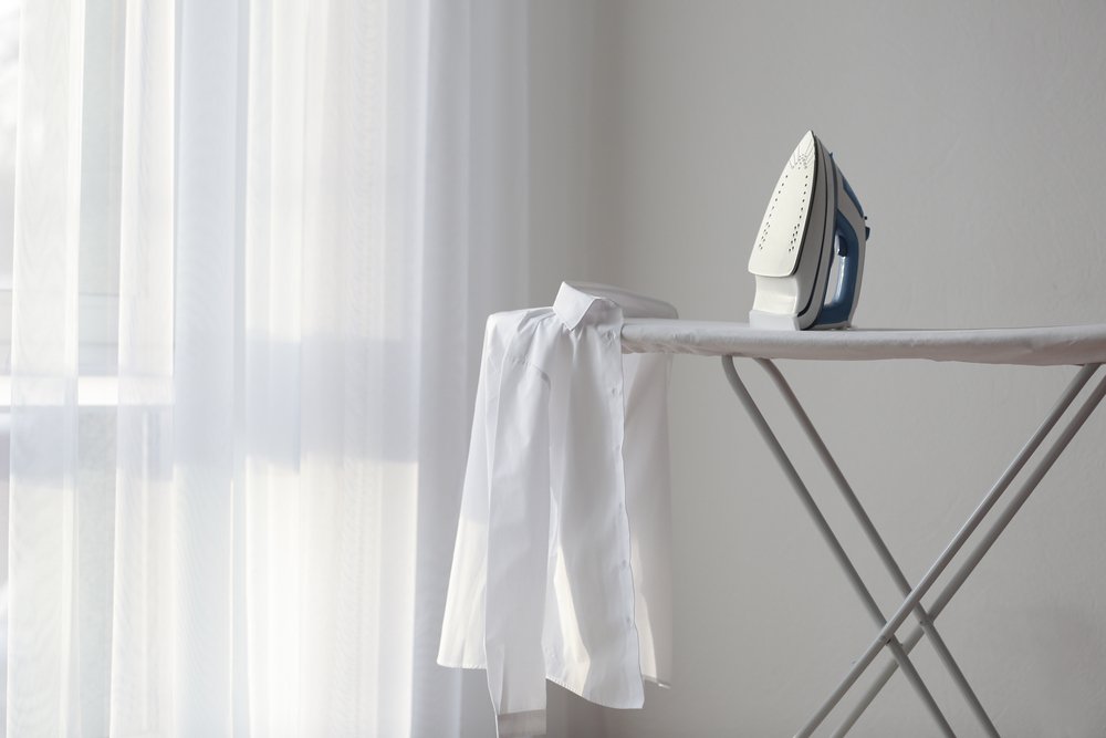 A photo of iron, shirt, and ironing board. | Photo: Shutterstock