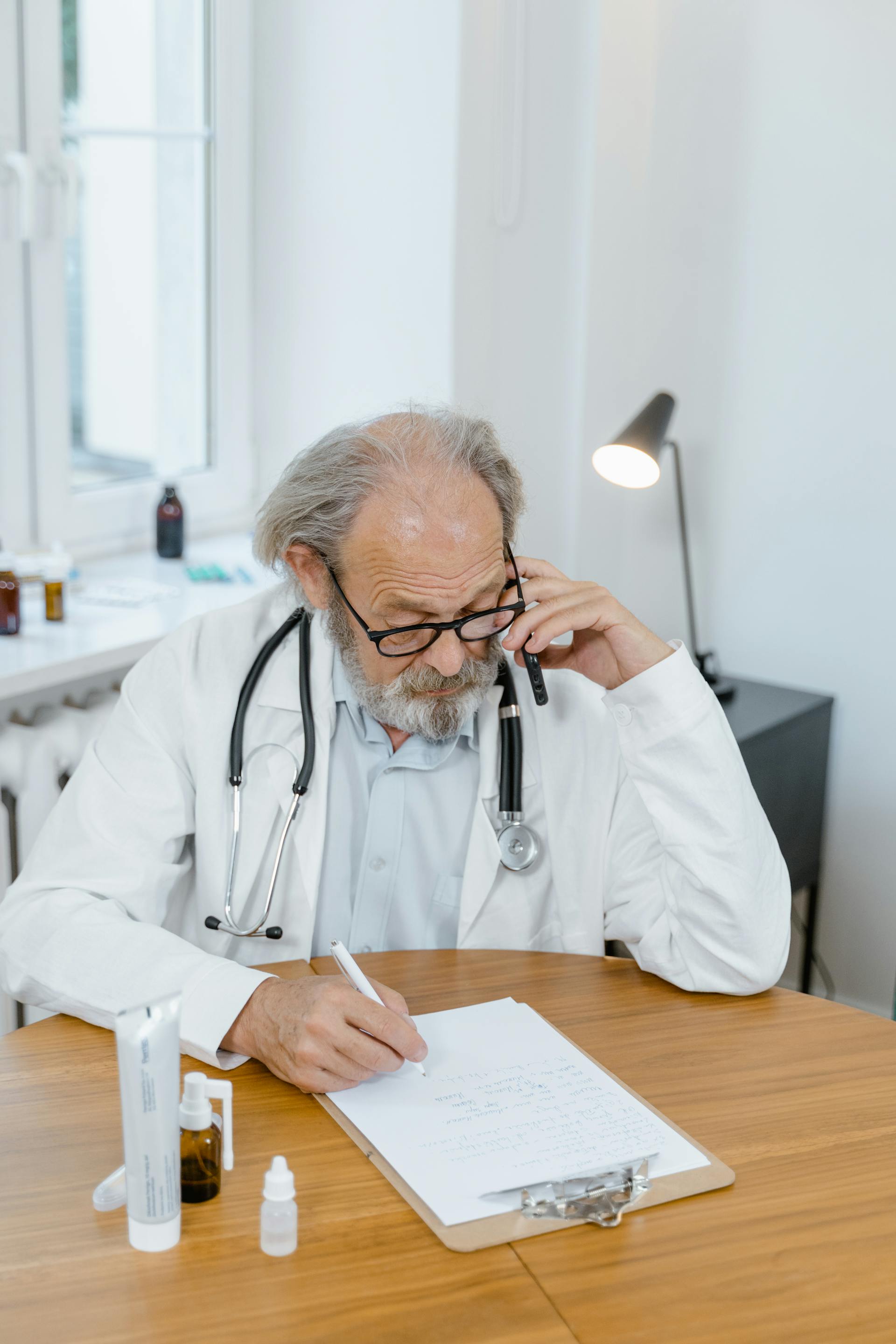 A doctor on the phone and writing | Source: Pexels