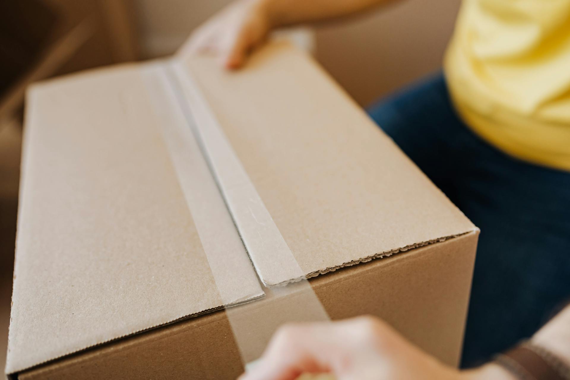 A person with a brown cardboard box | Source: Pexels