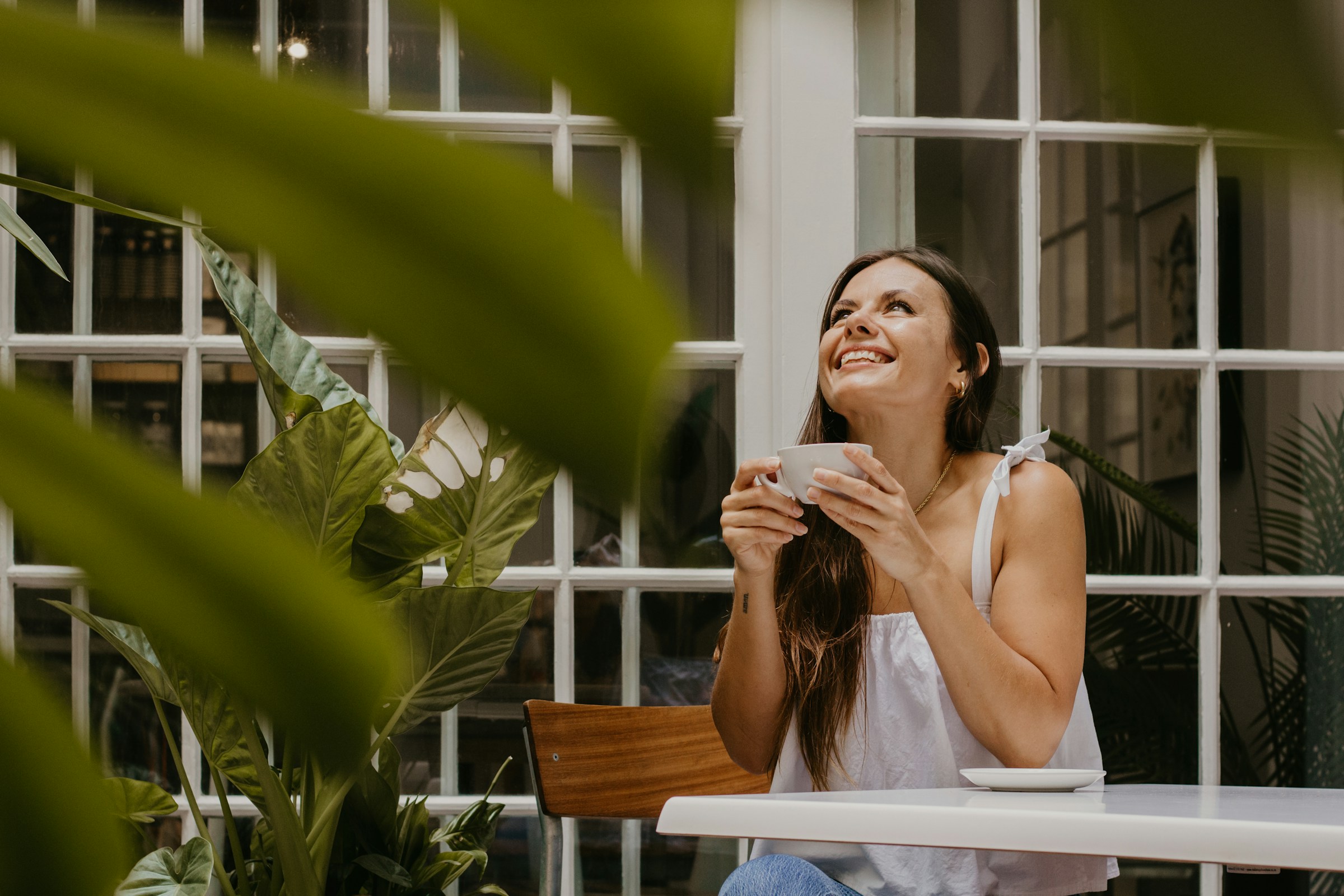 A young woman smiles while holding a cup of coffee | Source: Unsplash