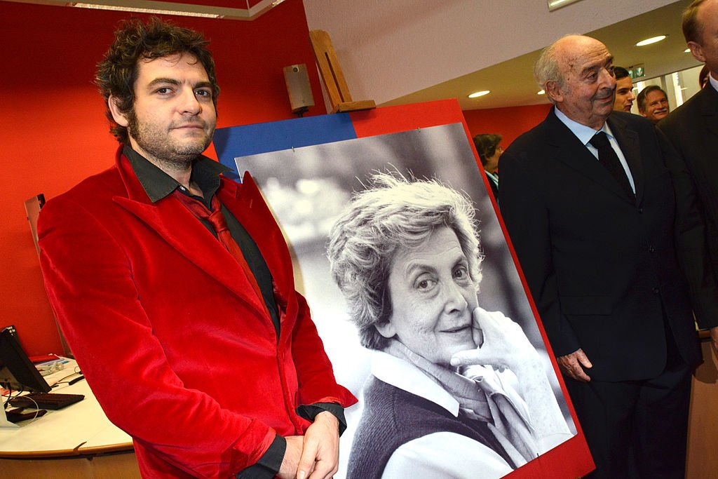 Matthieu Chedid et son grand père Louis Antoine Chedid posent avec le portrait d'Andrée Chedid. | Photo : Getty Images