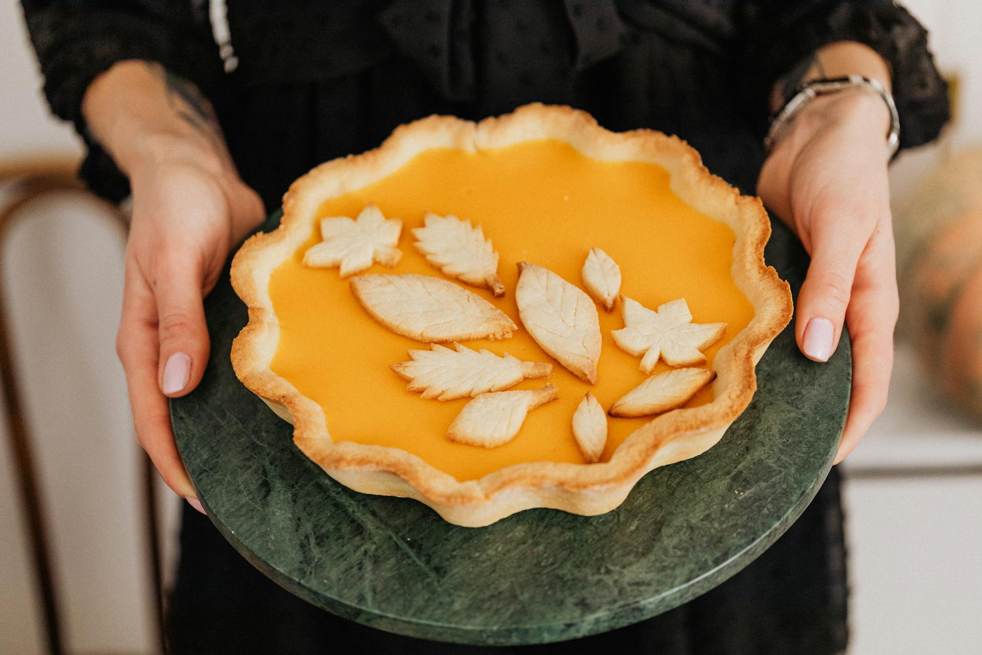 A woman holding a pumpkin pie | Source: Pexels