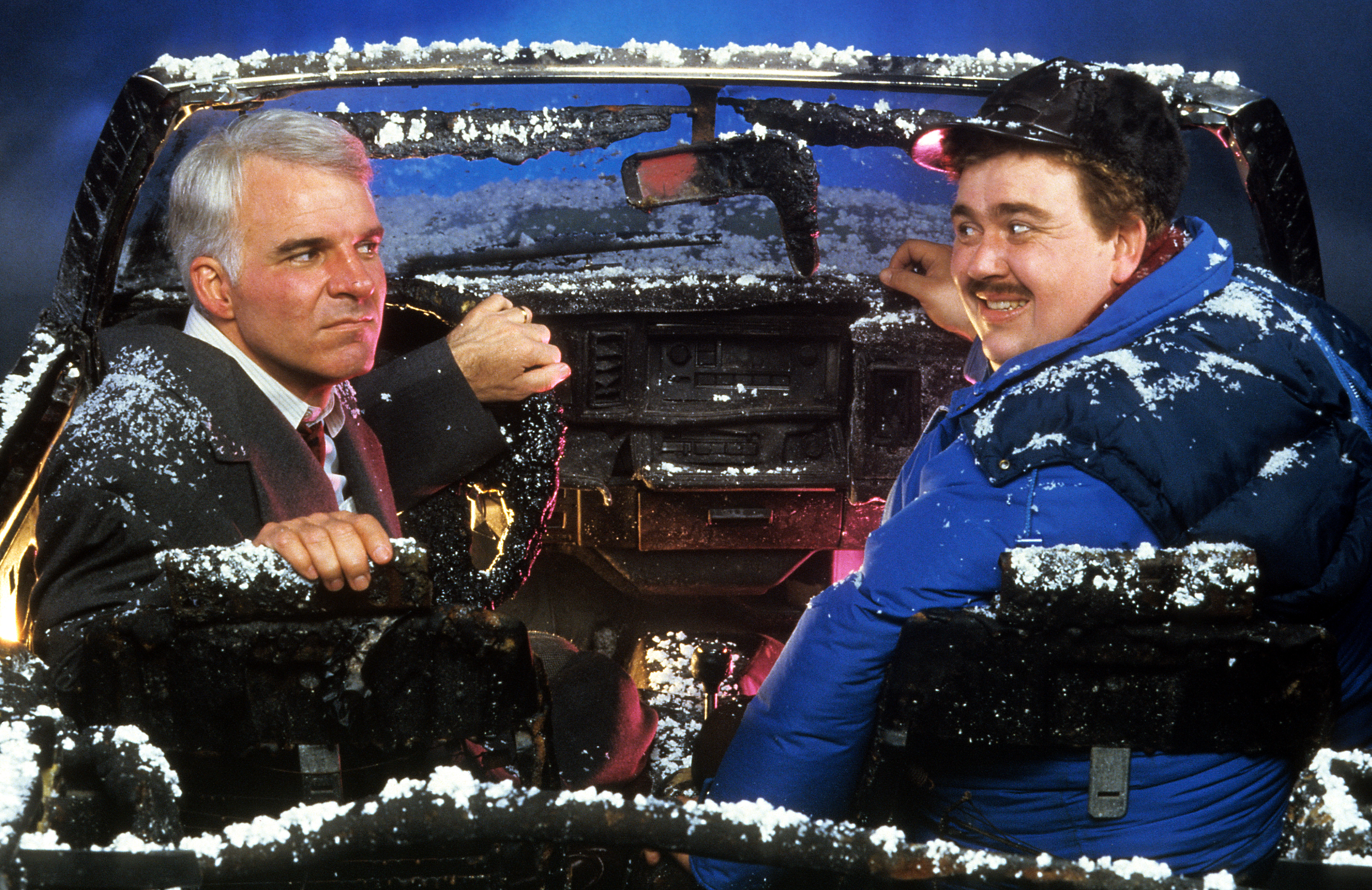 Steve Martin and John Candy sit in a destroyed car in a scene from the film "Planes, Trains & Automobiles", 1987. | Source: Getty Images