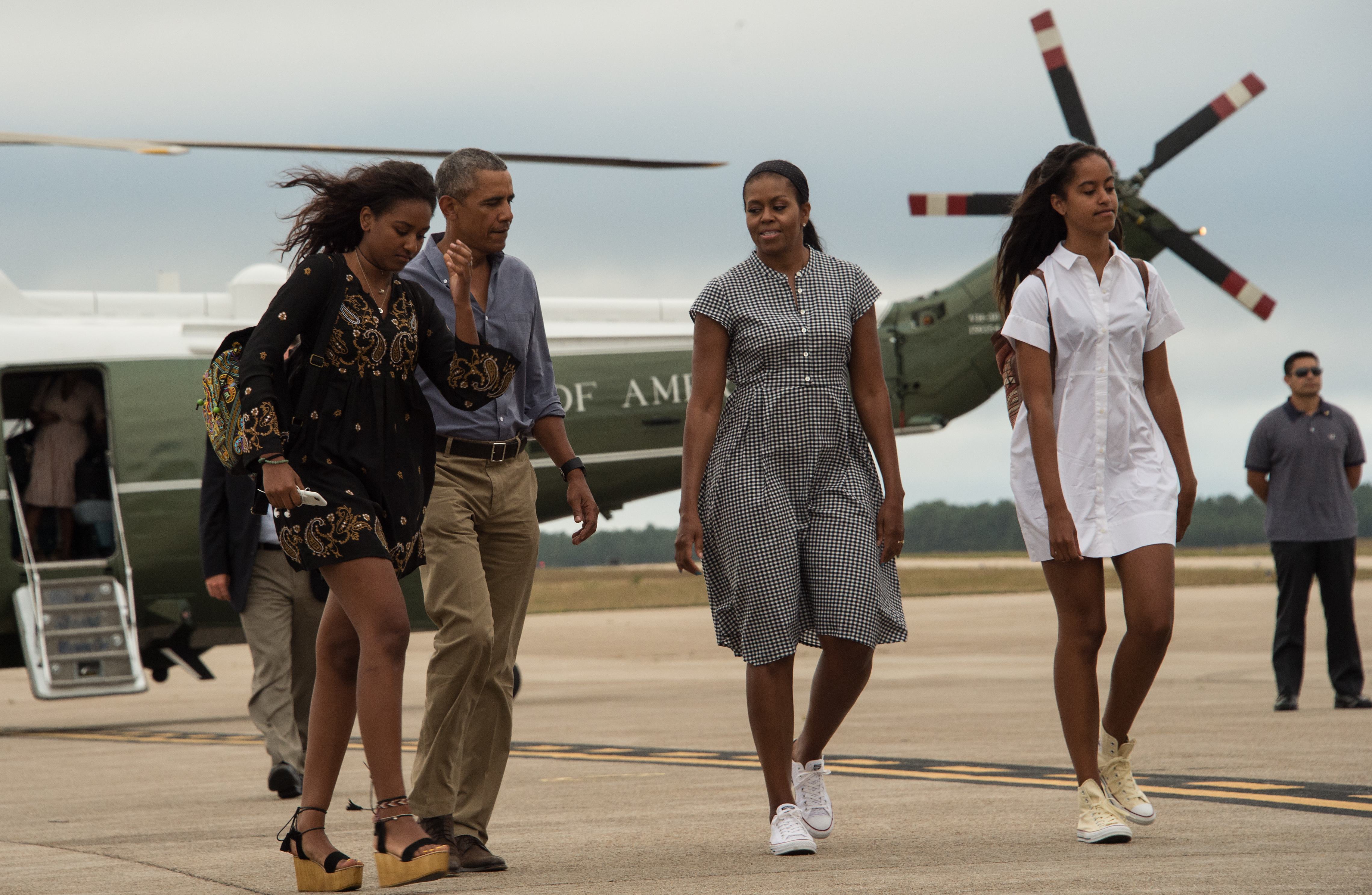 Barack Obama, Michelle Obama, and daughters Malia and Sasha walk to board Air Force One at Cape Cod Air Force Station in Massachusetts on August 21, 2016, as they depart for Washington after a two-week holiday at nearby Martha's Vineyard. | Source: Getty Images