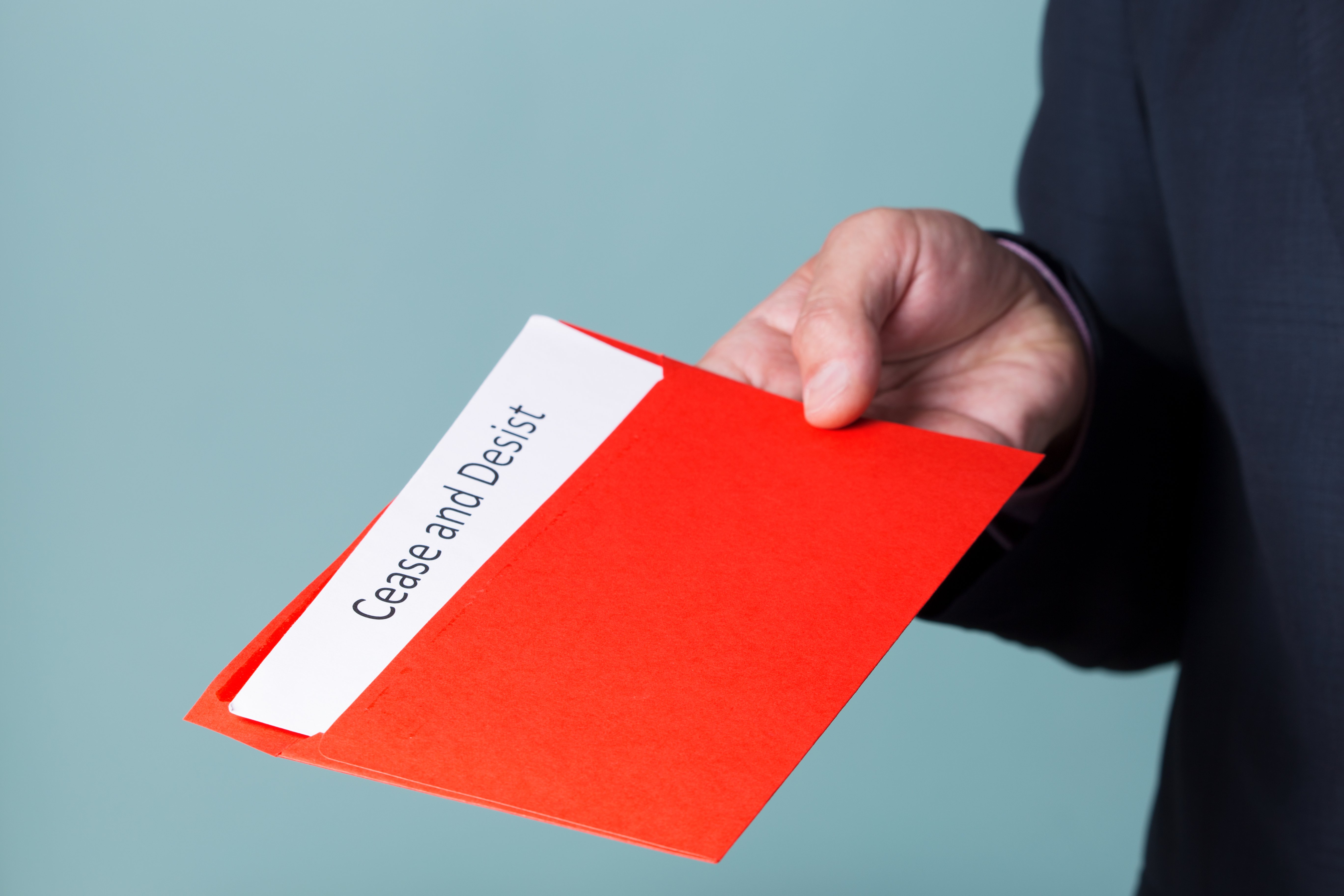 A man holding a cease and desist letter in red folder. | Source: Shutterstock