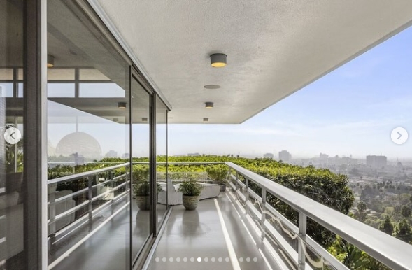 The home's wraparound terrace extends along its glass exterior, creating an outdoor passage with broad views across Los Angeles. Metal railings preserve the open sightlines, while potted plants and dense greenery along the edge add privacy without taking away from the property's elevated hillside outlook. | Source: Instagram/jparkerstanton
