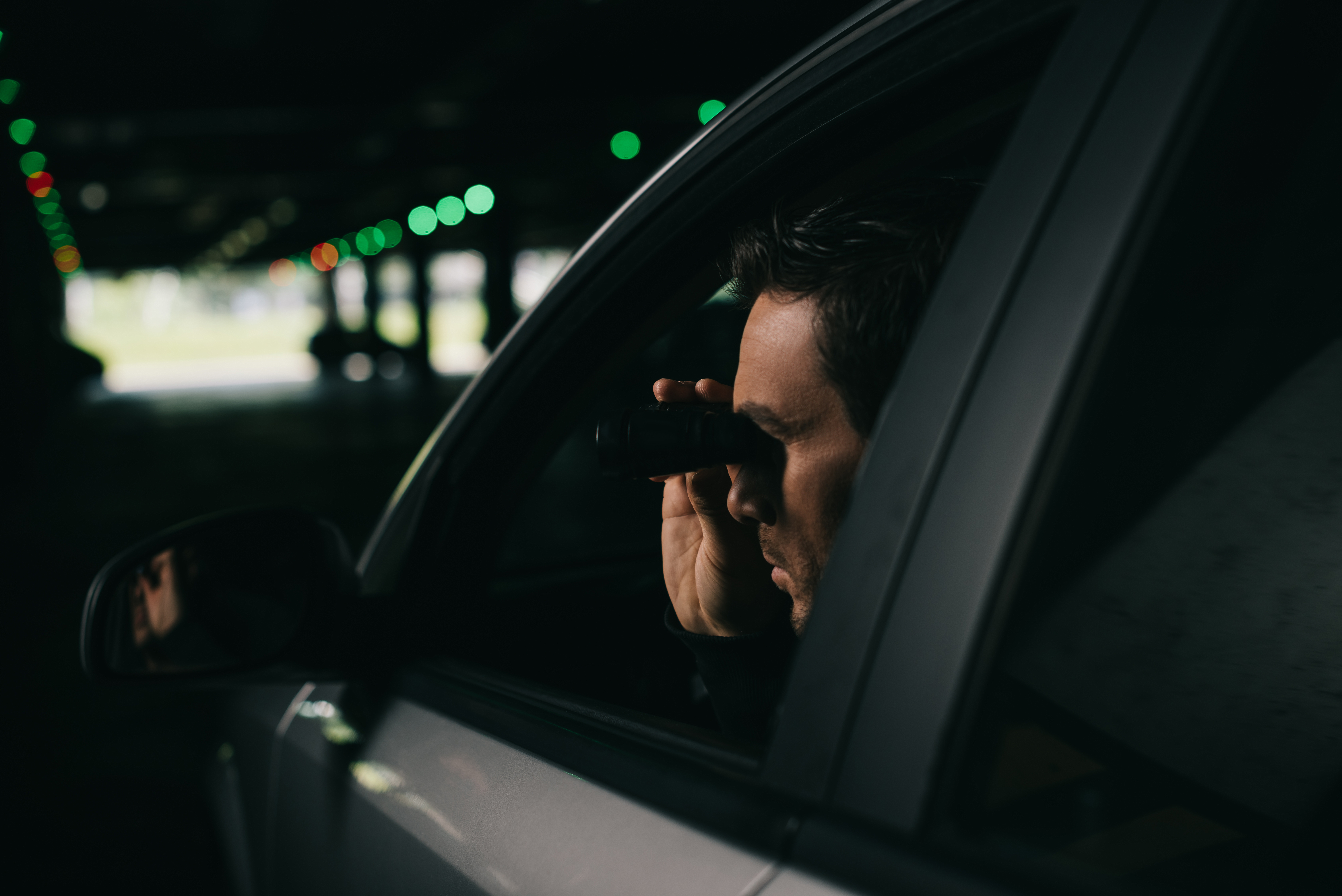 A man using binoculars while sitting in his car | Source: Shutterstock