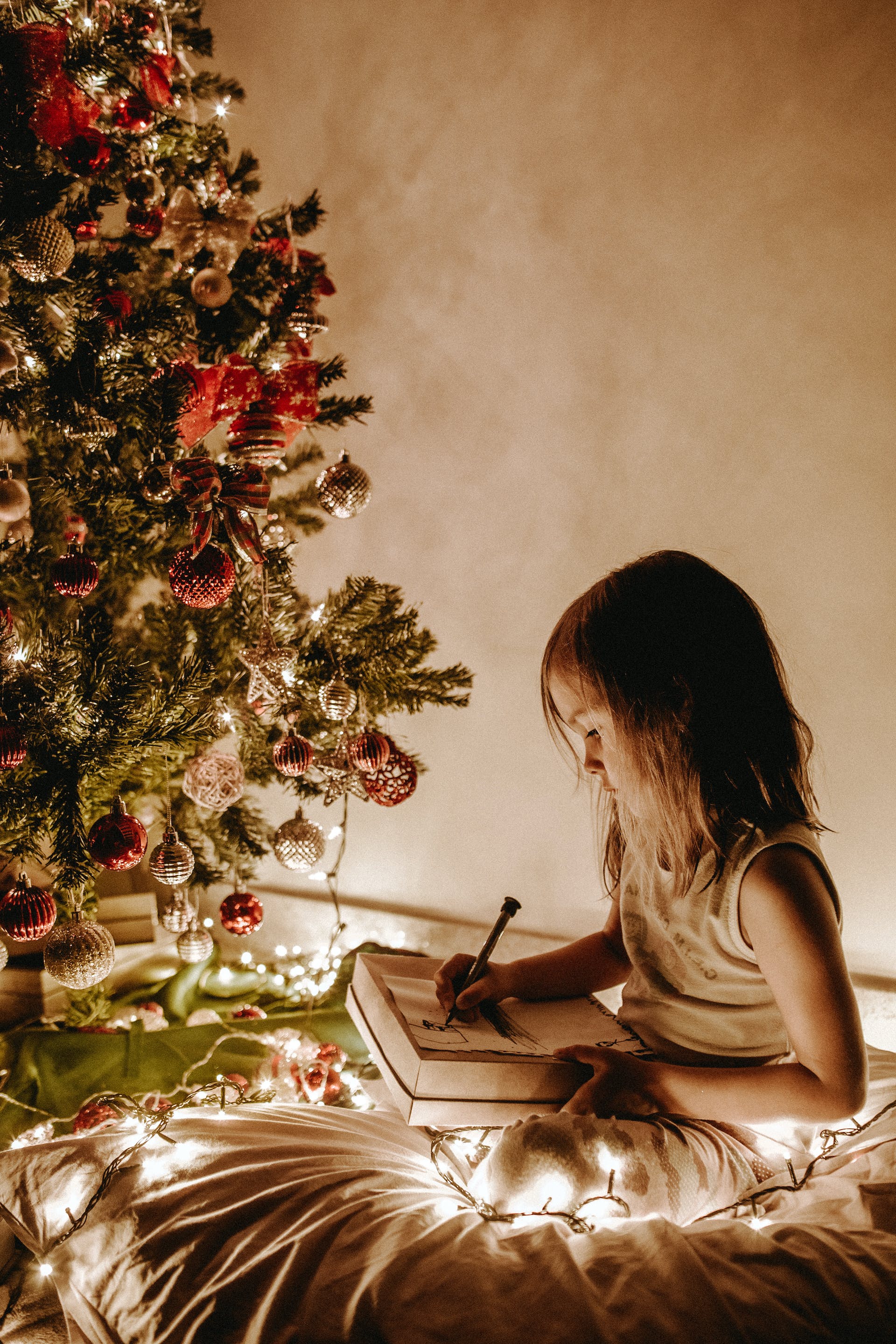 A little girl sitting near a Christmas tree | Source: Pexels