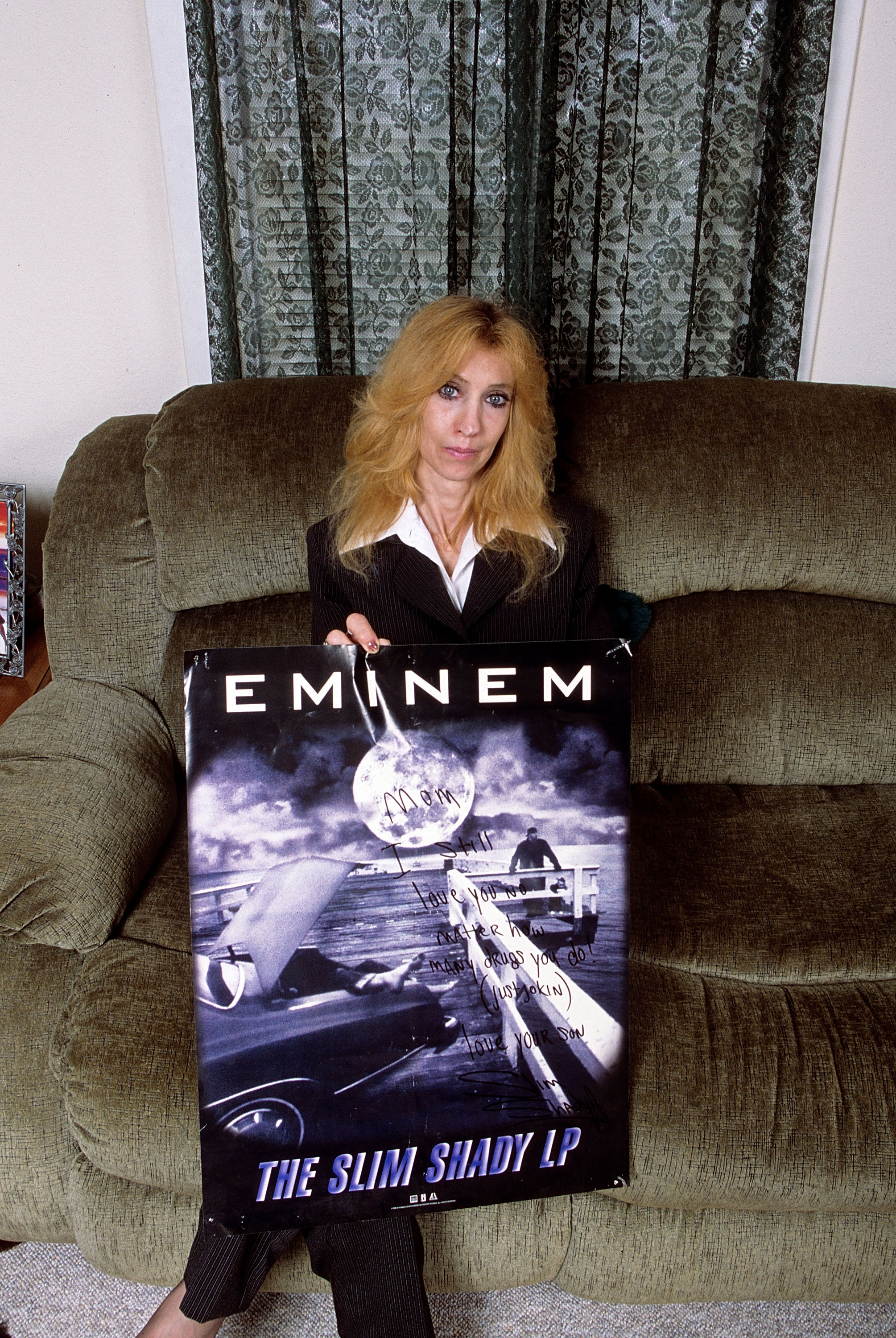 Eminem's mother, Debbie Nelson, holds a poster with a handwritten message during a portrait session at her home in September 2005 in Detroit, Michigan. | Source: Getty Images