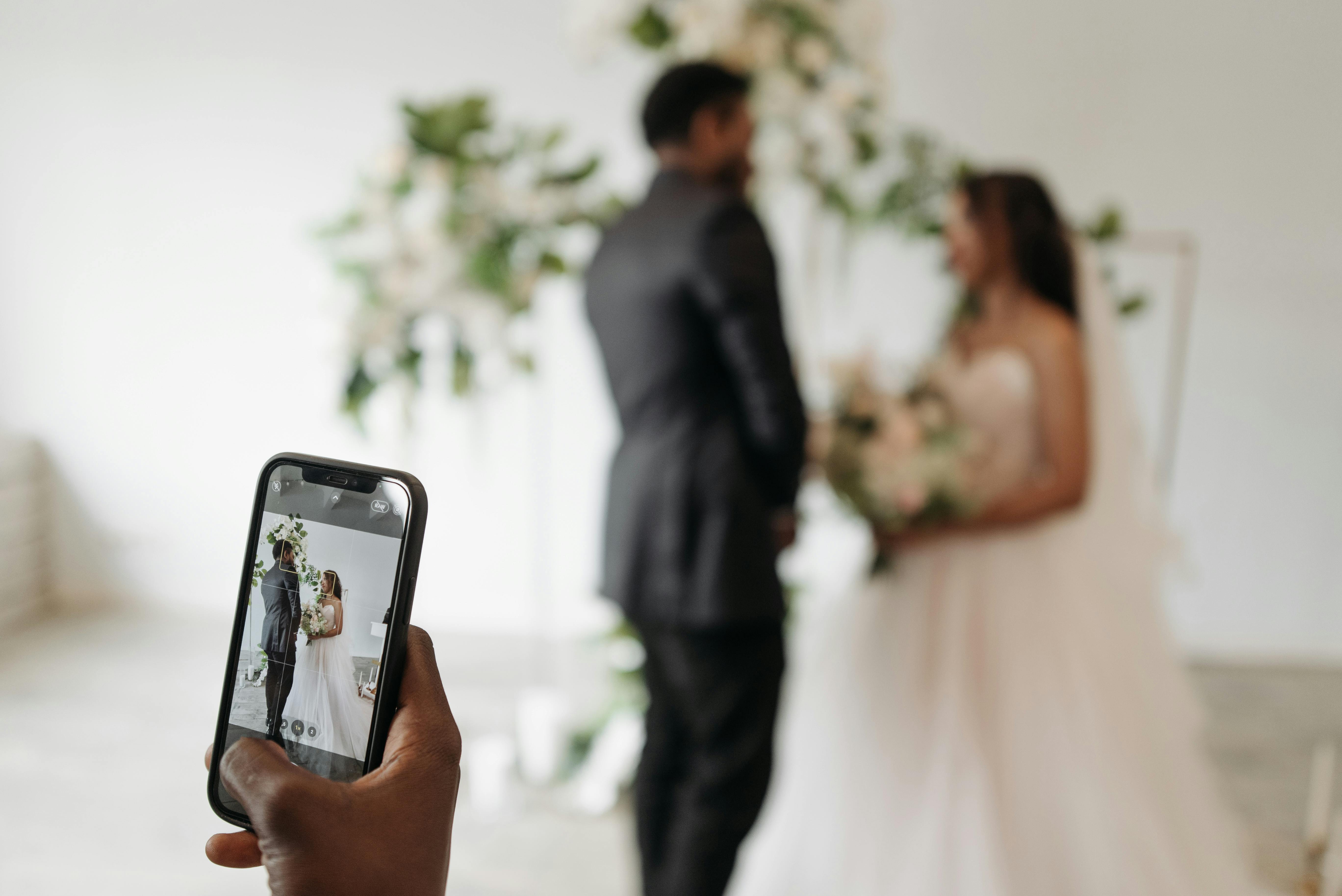 Someone recording a newlywed couple on their phone | Source: Pexels
