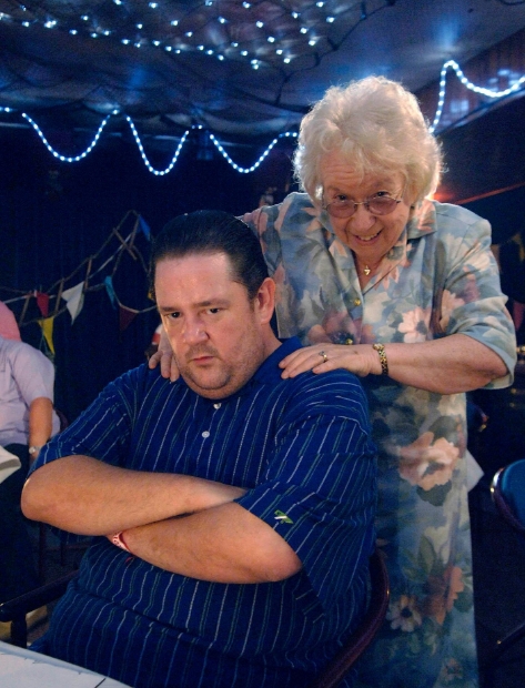 Elsie Kelly appears alongside Johnny Vegas in a scene from "Benidorm," highlighting their on-screen chemistry as mother and son. | Source: Facebook/WalesOnline