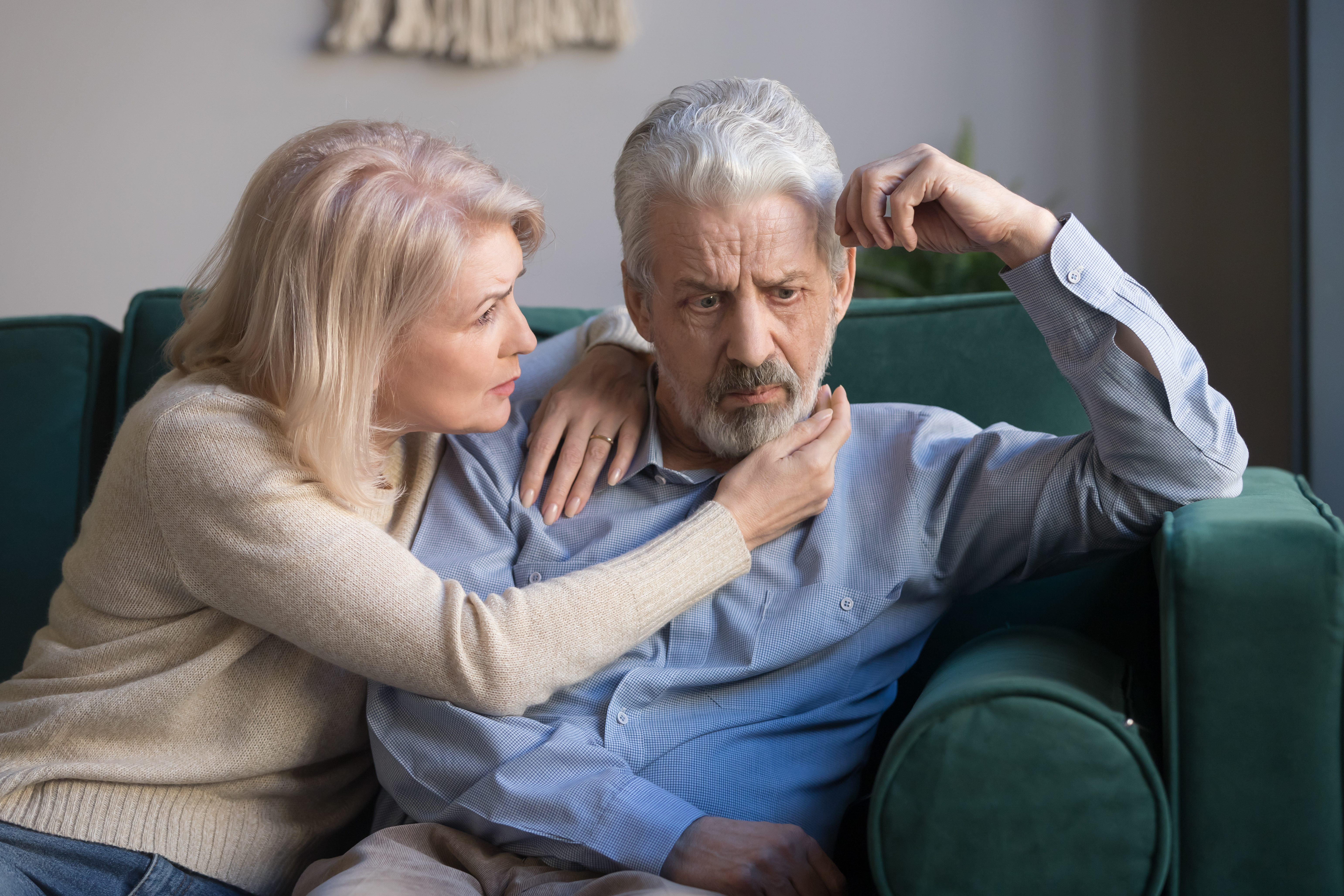 A middle aged wife comforting her upset grey-haired husband | Source: Shutterstock