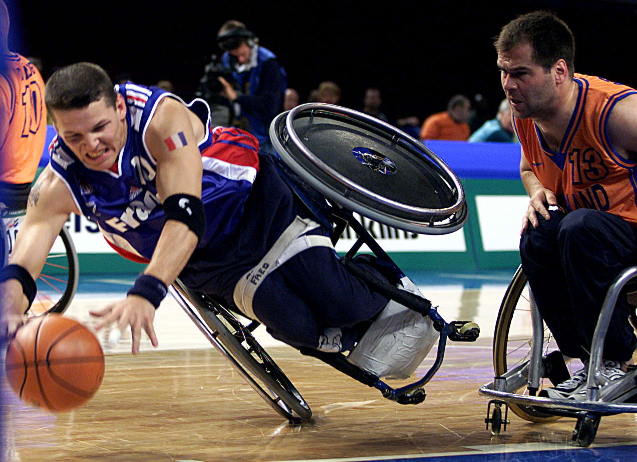 Frederic Guyot of France dives for the ball while Rene Martens of the Netherlands watches on during the Wheelchair Basketball match between France and the Netherlands held at the Sydney Superdome during the Sydney 2000 Paralympic Games | Source: Getty Images