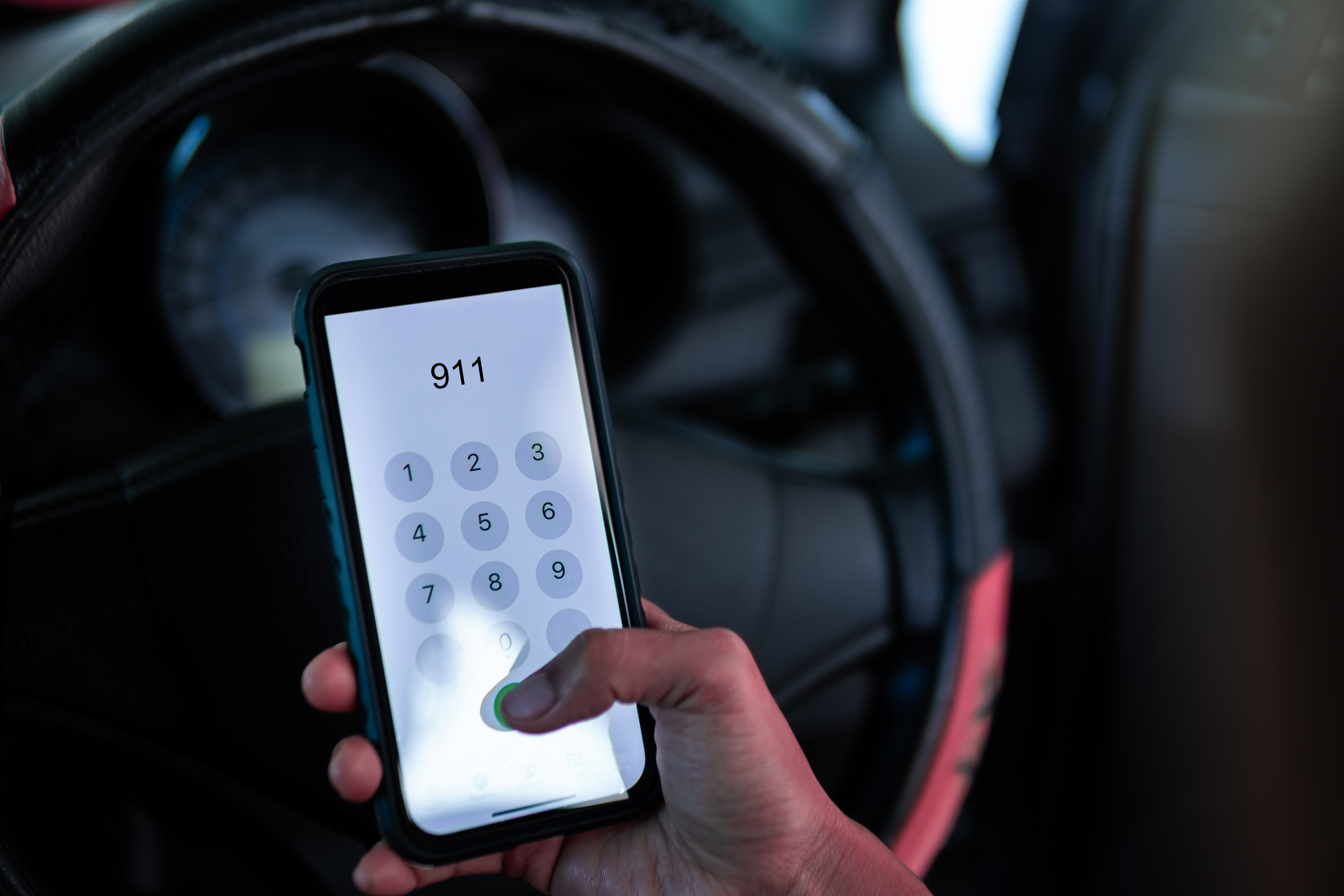 Hand holding cell phone with emergency number 911 in car. | Source: Shutterstock